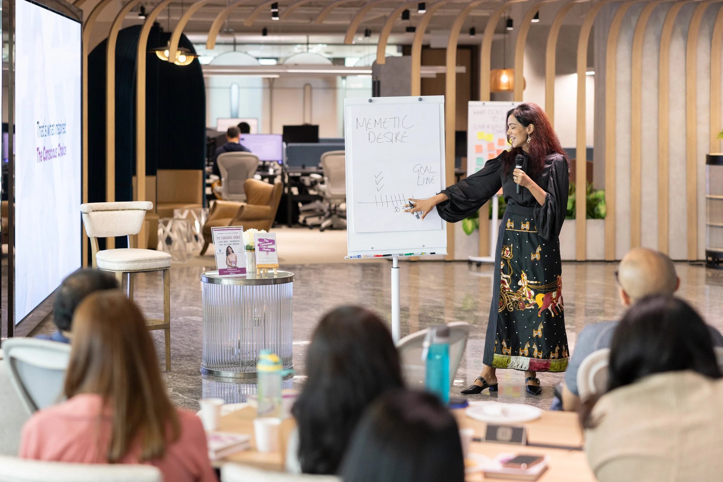  Medium perspective of Bhavna Toor highlighting key concepts on the presentation board. 