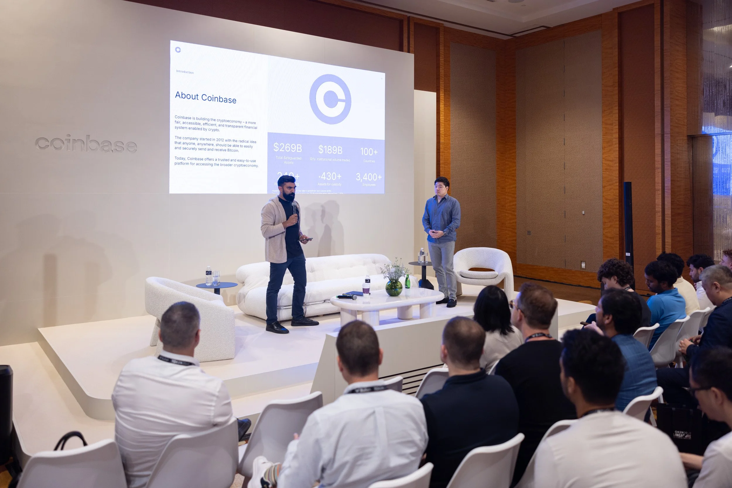  Wide stage photograph of keynote speakers presenting at the Coinbase Token 2049 conference stage. 