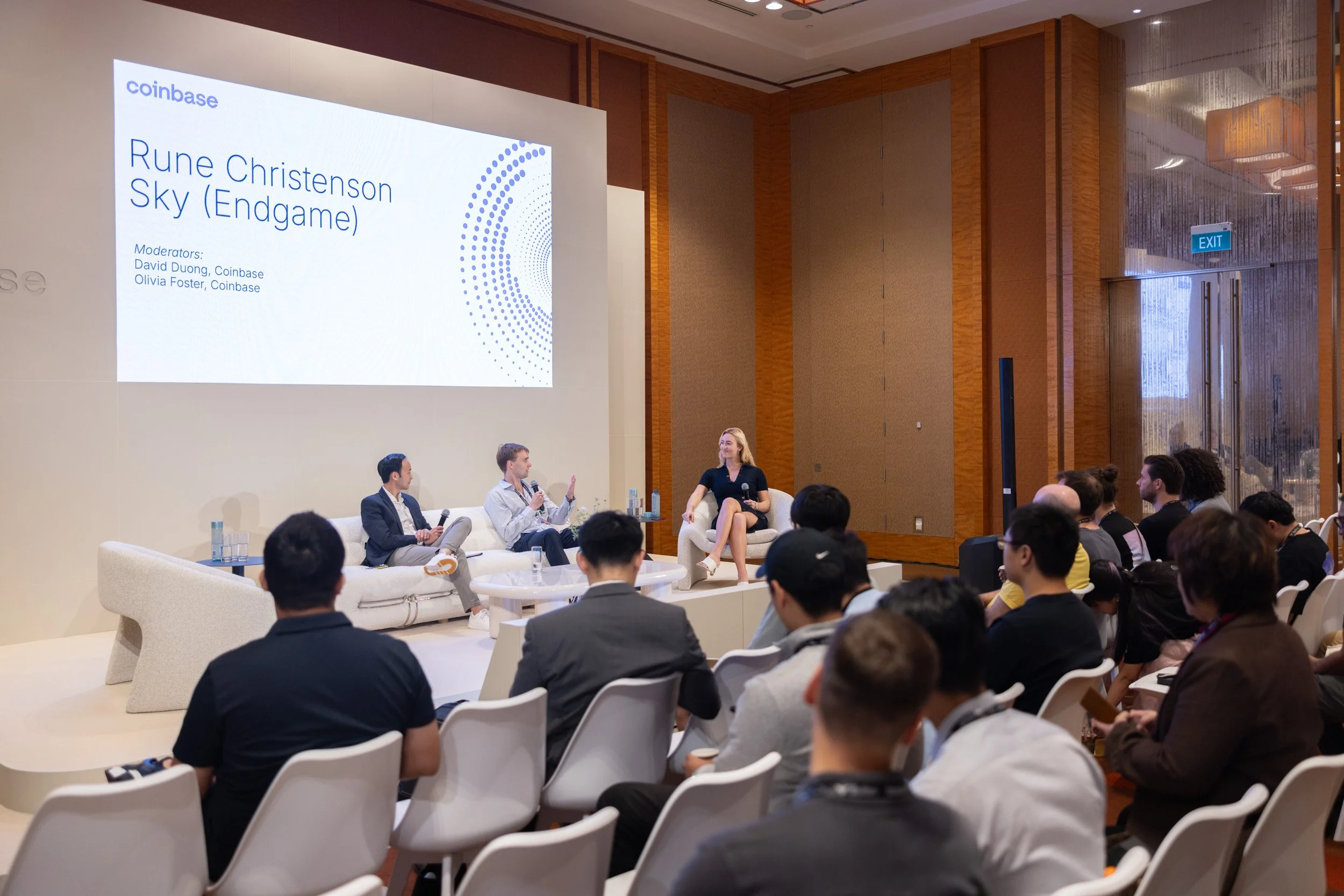  Wide stage photograph of Rune Christensen speaking alongside David Duong and Olivia Foster during a session. 