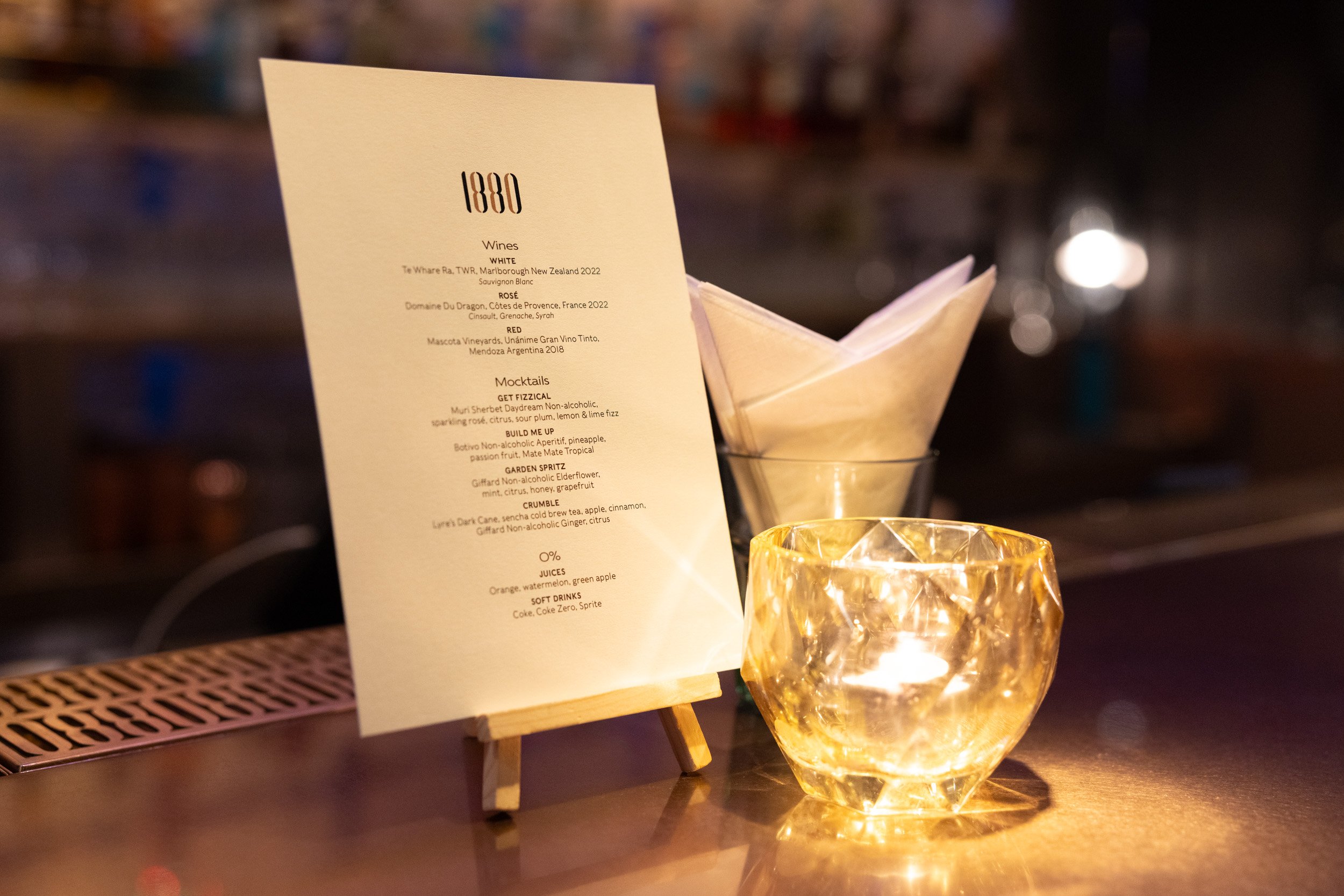  Close-up of the custom 1880 Singapore event beverage menu table stand featuring wine and mocktail selections. 