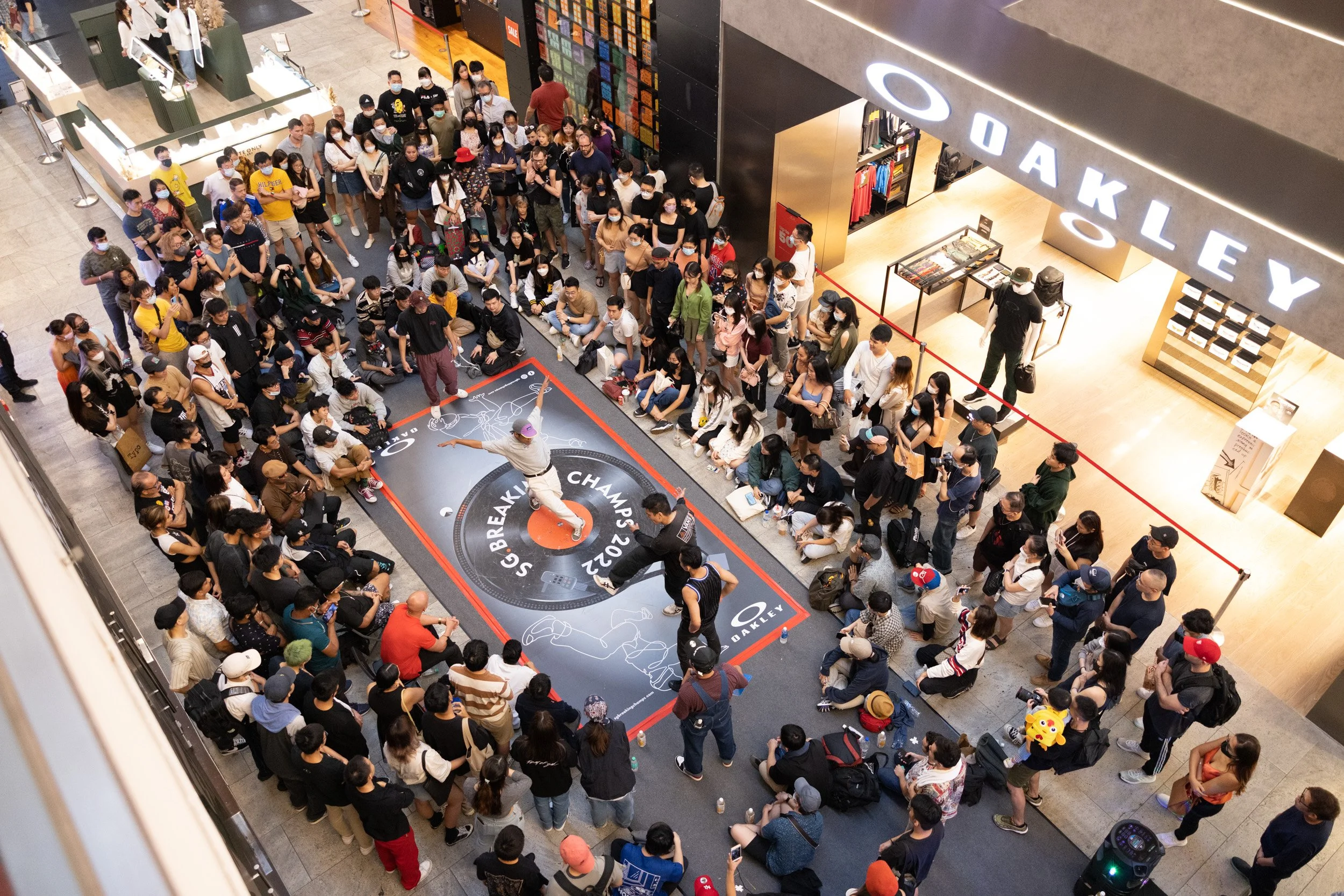  Elevated wide-angle photograph of a breaker performing top rock routines in front of the Oakley flagship storefront. 