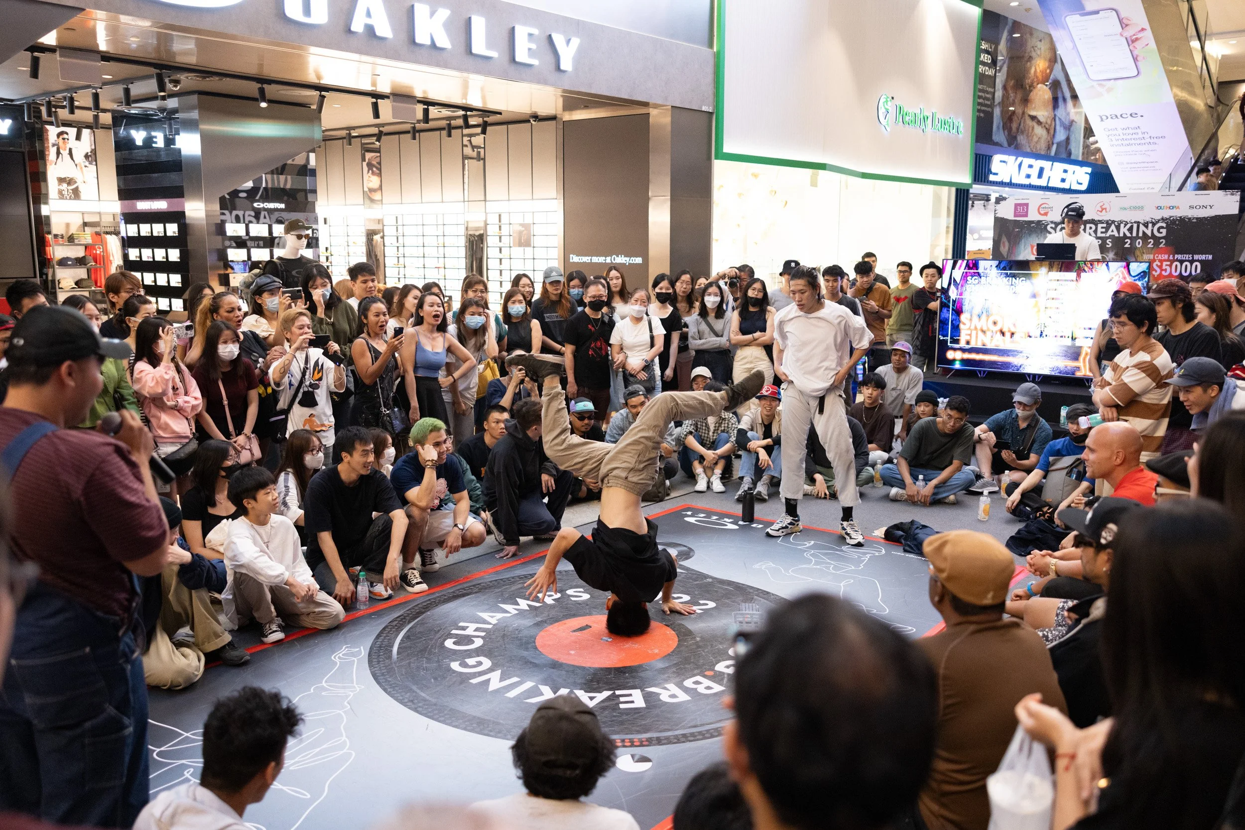  Mid-range action shot of a B-boy executing a headspin on the event stage floor. 