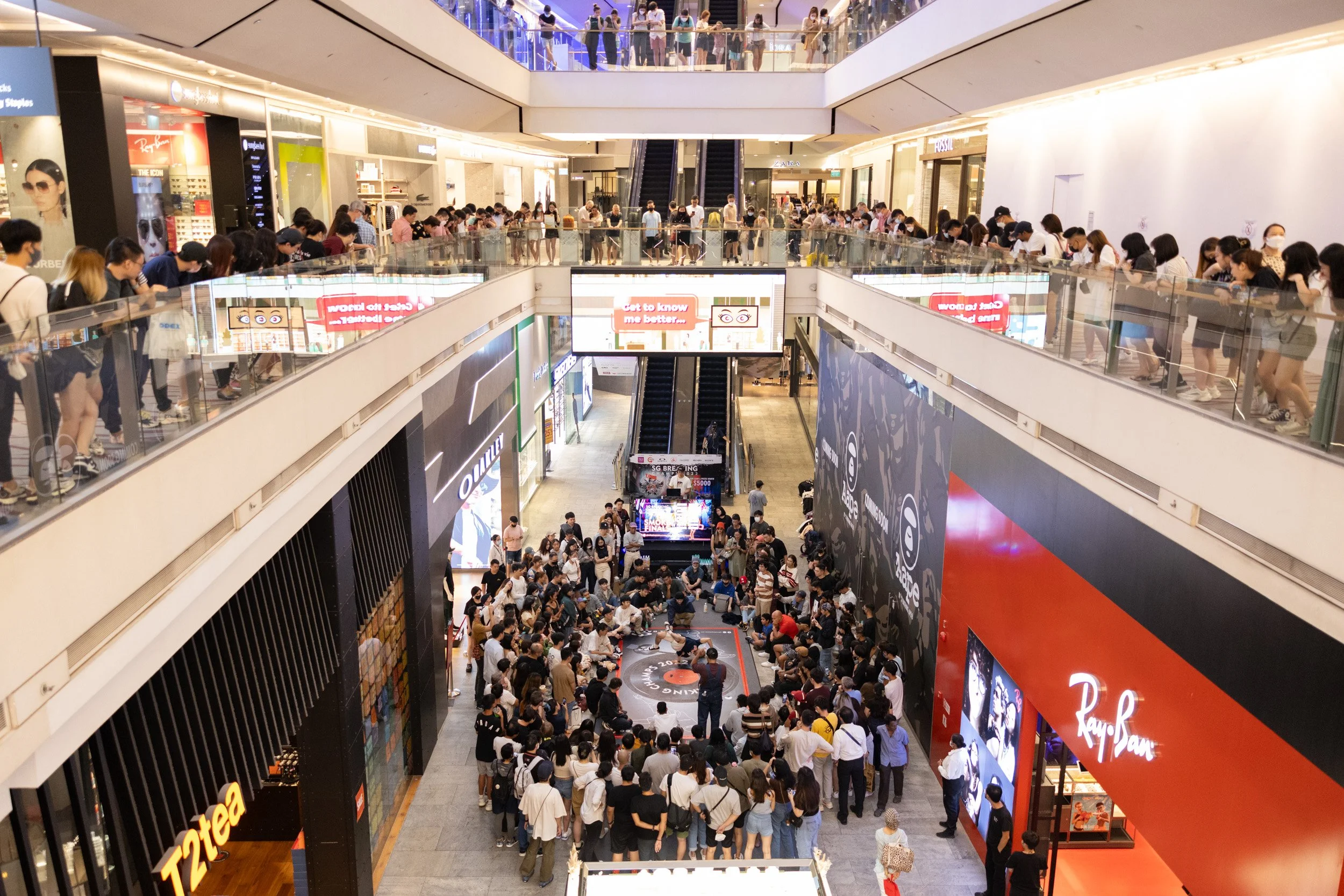  Elevated wide-angle view of spectating crowds gathered across multiple atrium balcony floors at 313@somerset. 