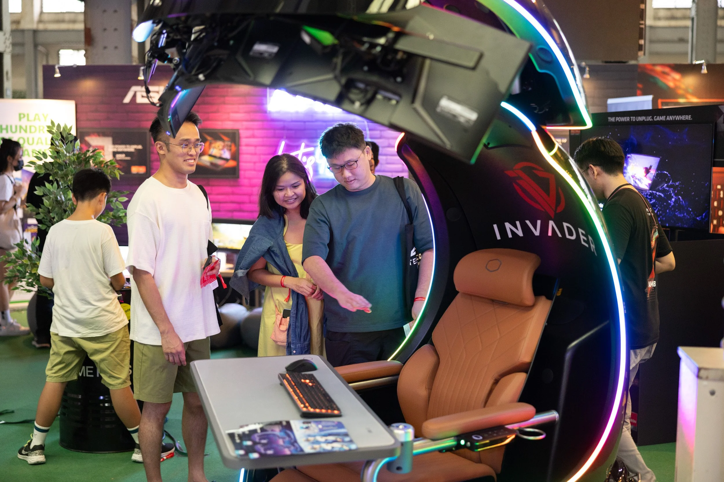  Event attendees exploring the custom Invader PC simulator pod at the AMD experience zone. 