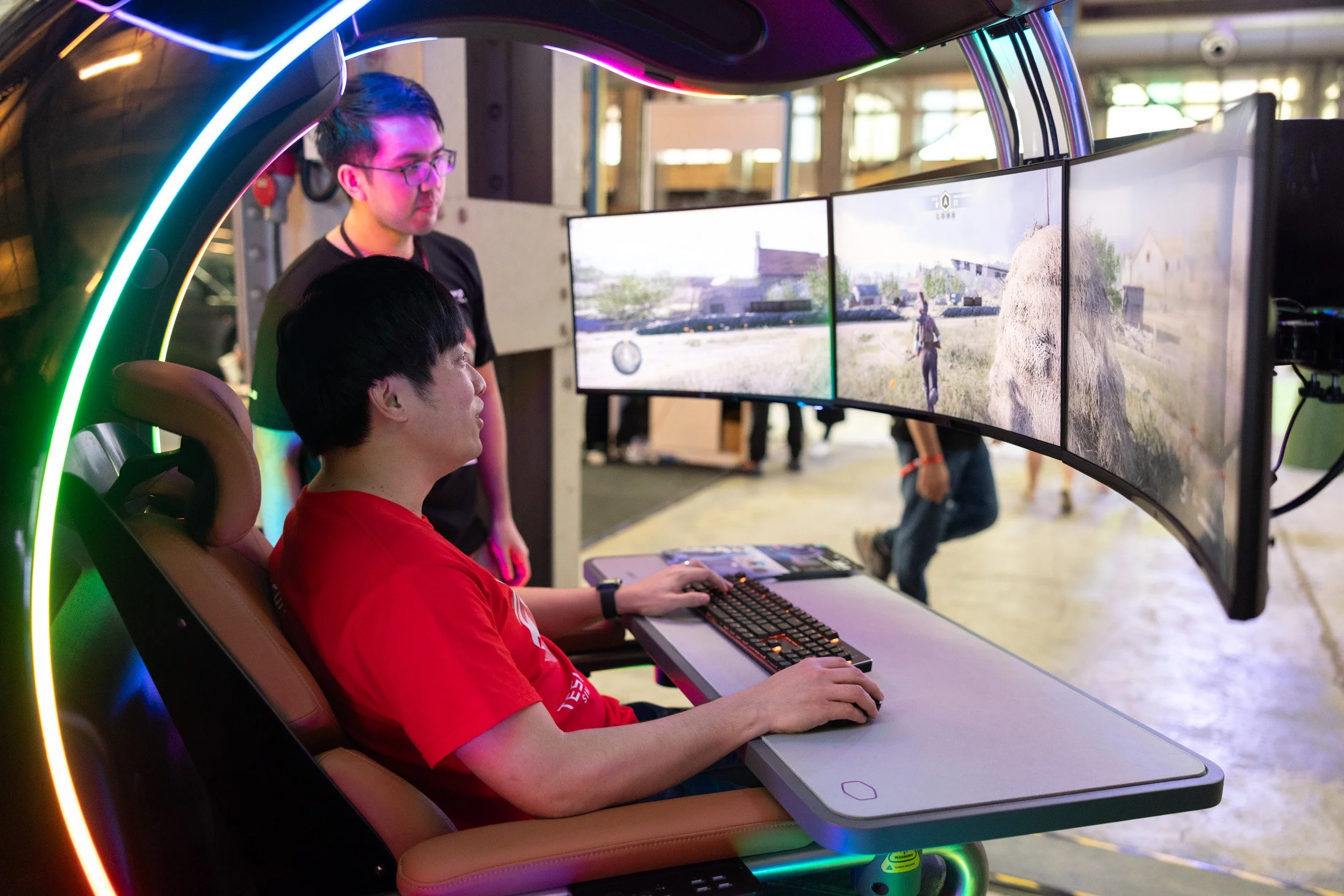  Gamer's perspective inside the Invader PC cockpit displaying racing gameplay across triple surround monitors. 