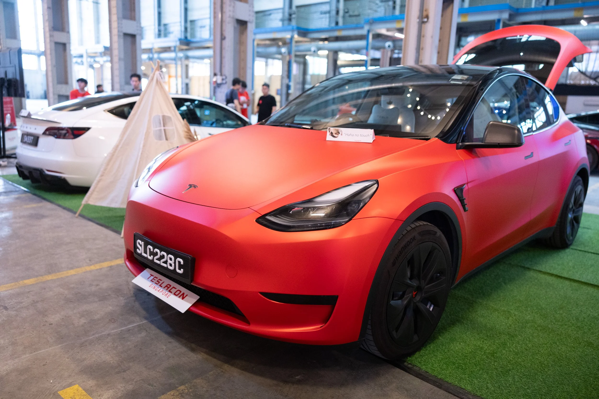 Detailed close-up shot of a red Tesla electric vehicle on display at TeslaCon Singapore 2023. 