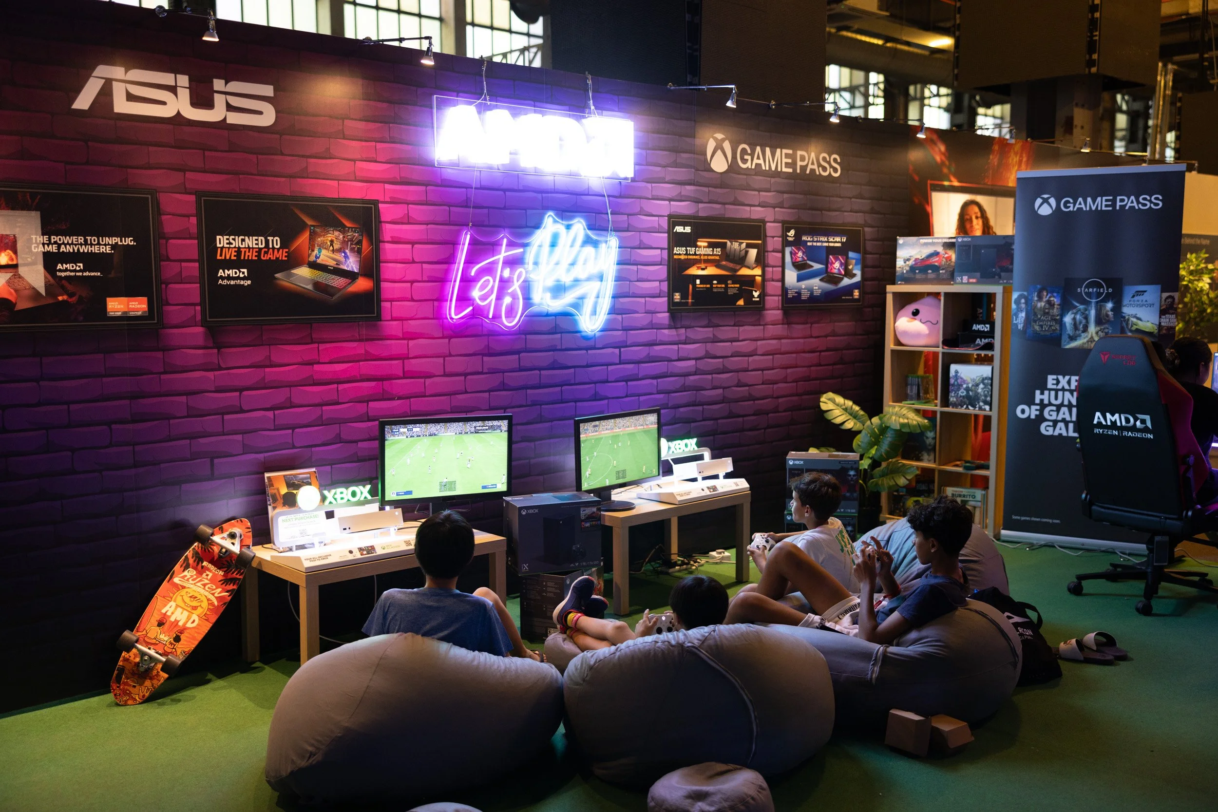  Wide-angle view of youth gaming stations featuring Xbox consoles and custom neon backlit display walls. 