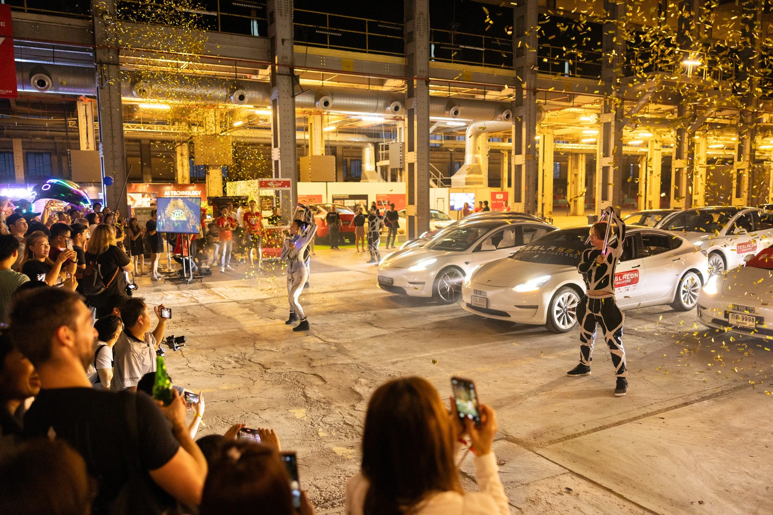  Grand finale of the stage dance performance featuring falling confetti surrounded by displayed Tesla models. 