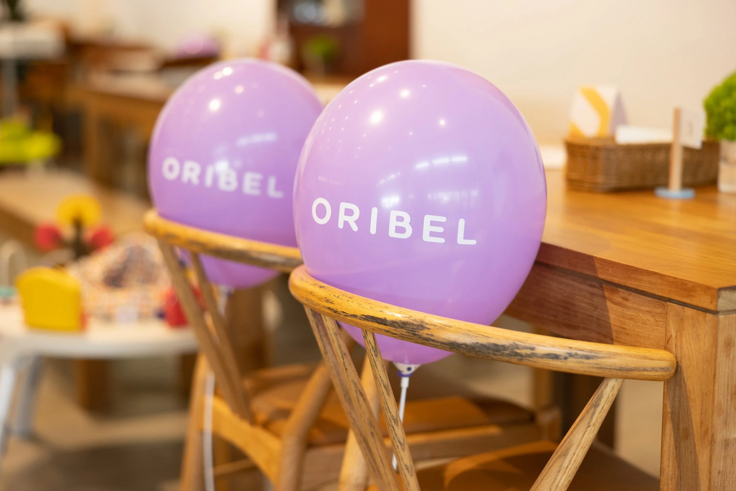  Close-up photo of a custom purple balloon printed with the Oribel logo tied to event seating. 