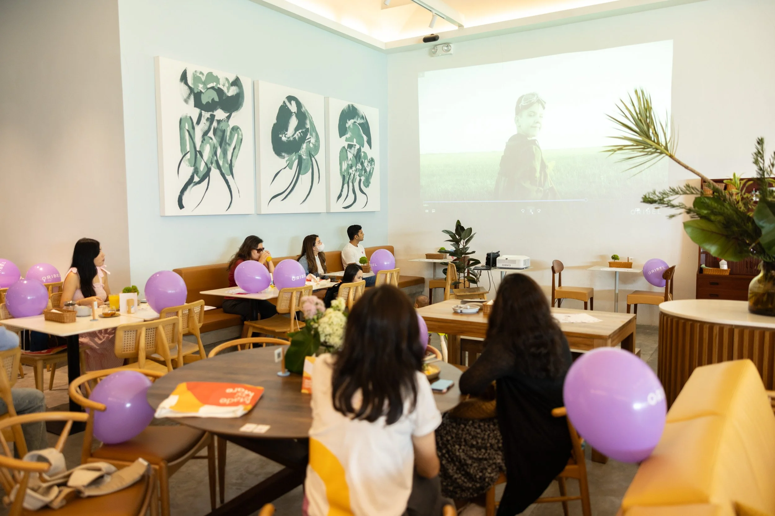  Wide-angle view of parents watching a brand video presentation projected on the wall. 