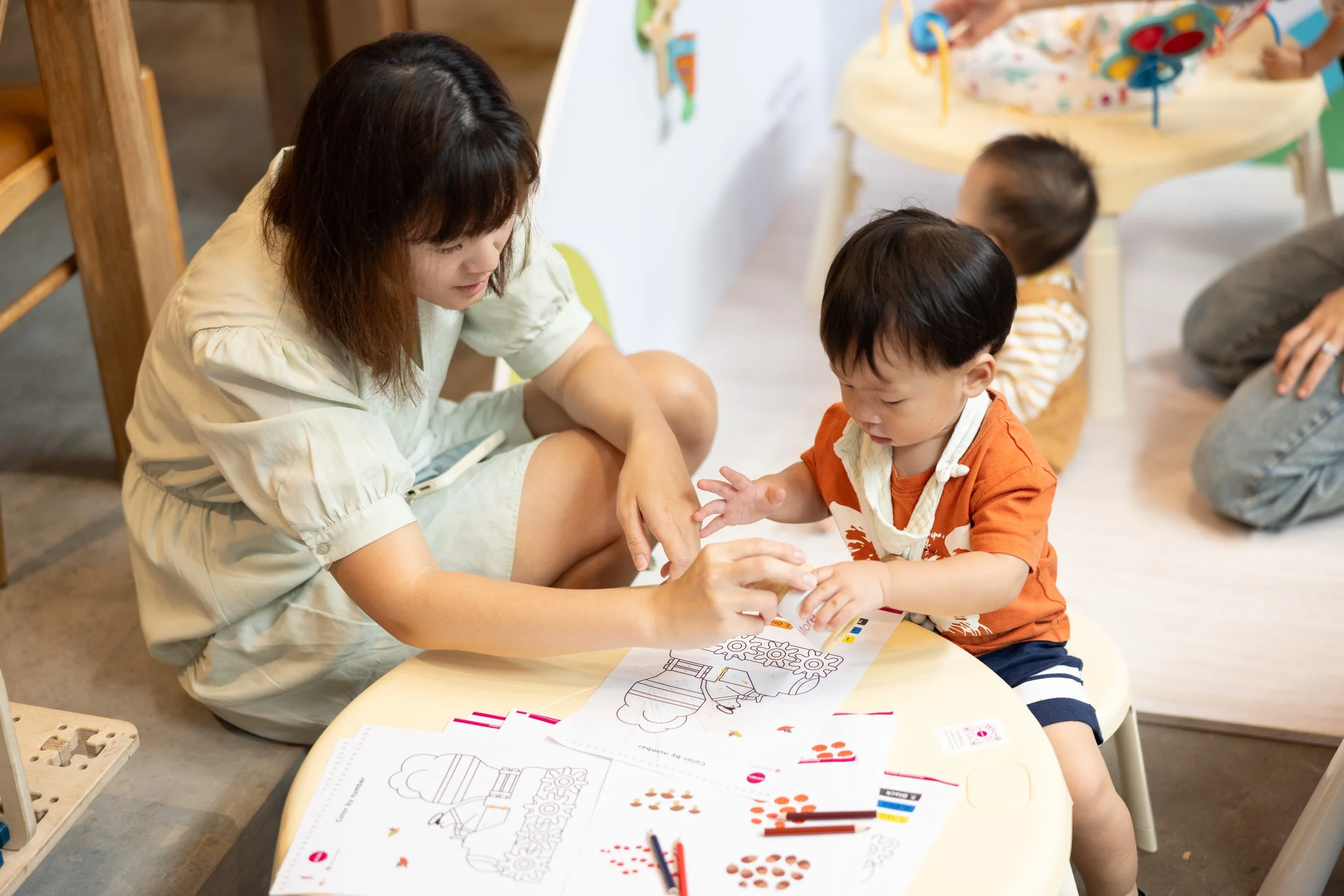  Mother and toddler completing an Oribel interactive paper puzzle at a low table. 