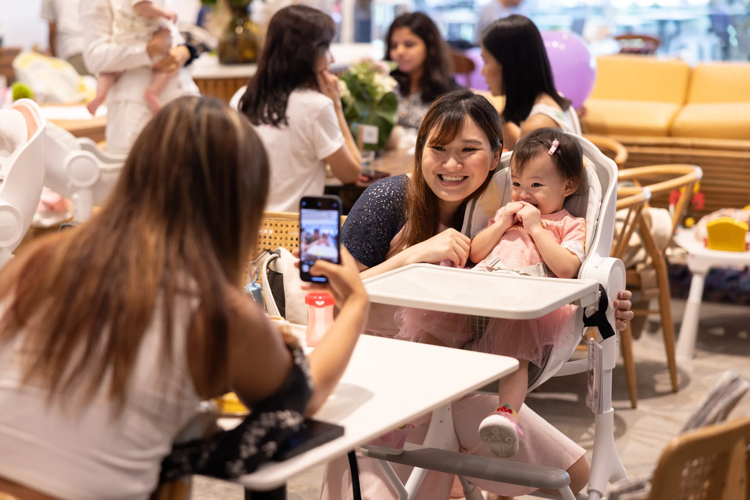  Candid moment of a mother posing with her child for a smartphone photo at the event. 