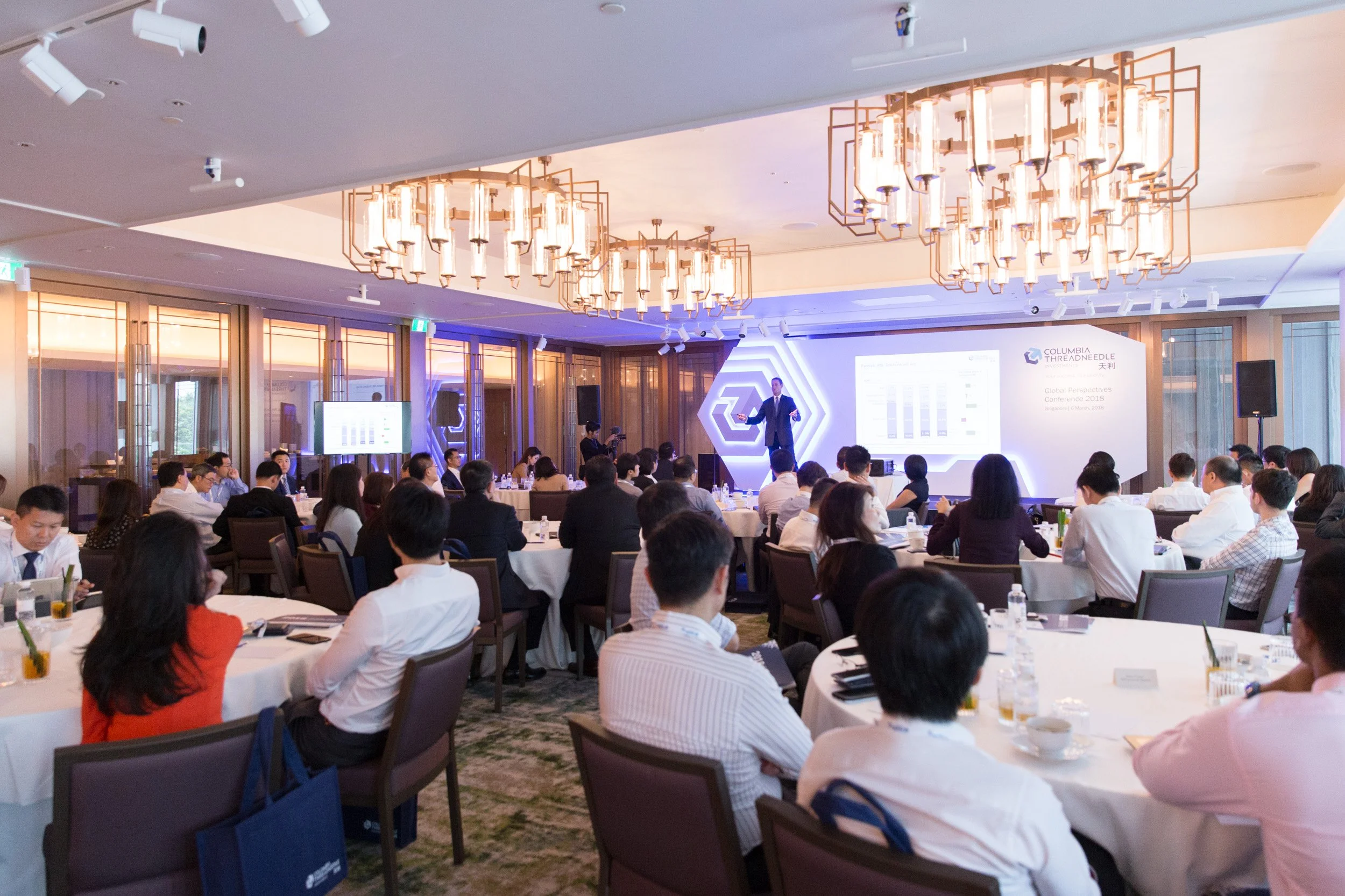 Side-angle view of the keynote presenter addressing conference delegates. 