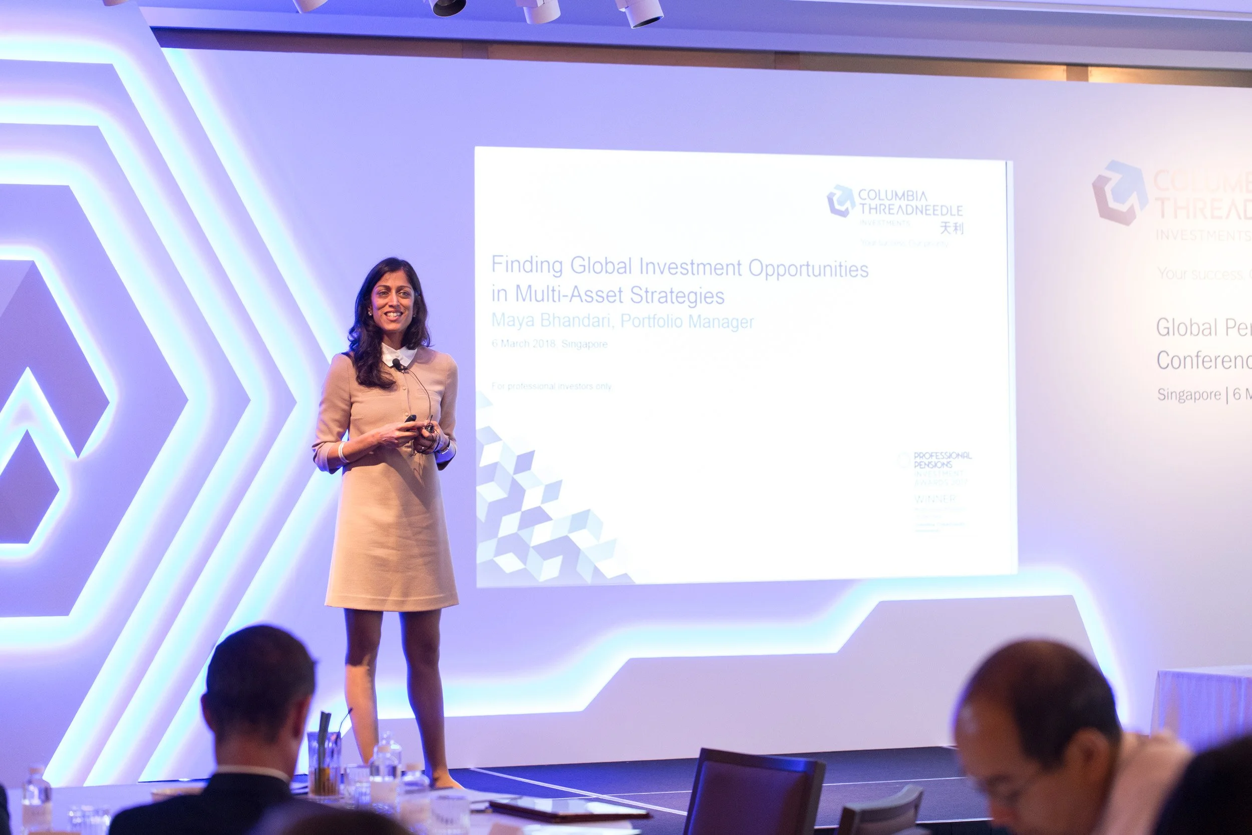  Female keynote speaker presenting investment insights on stage at the Global Perspectives Conference. 
