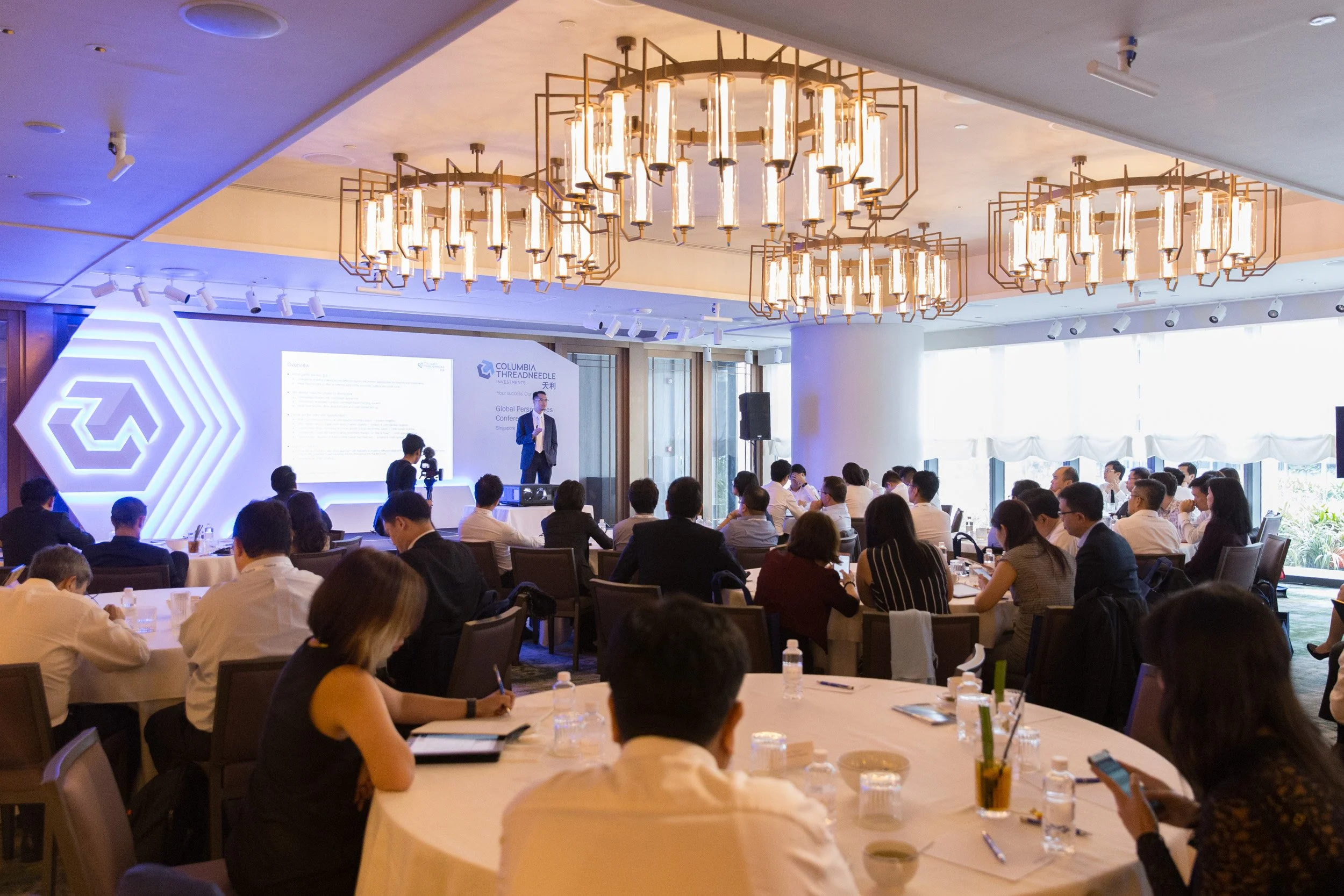  Wide perspective of the presentation stage and digital backdrop during the investment forum. 