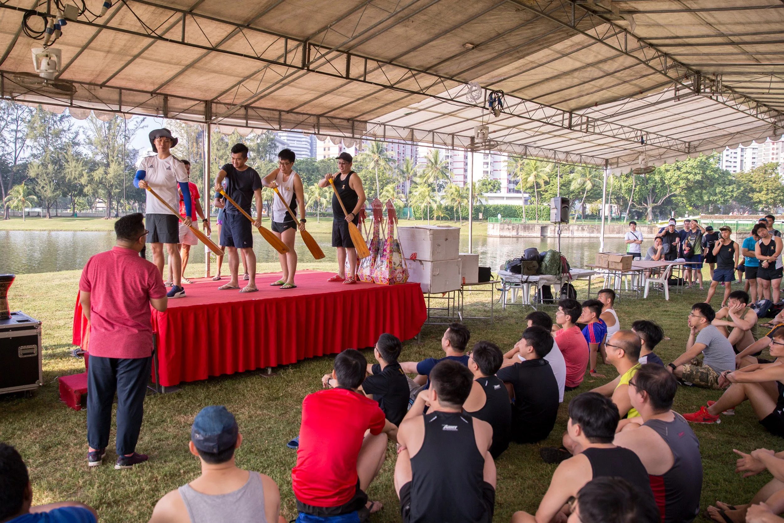  Four participants on stage demonstrating synchronized paddling technique during the land-based safety briefing. 