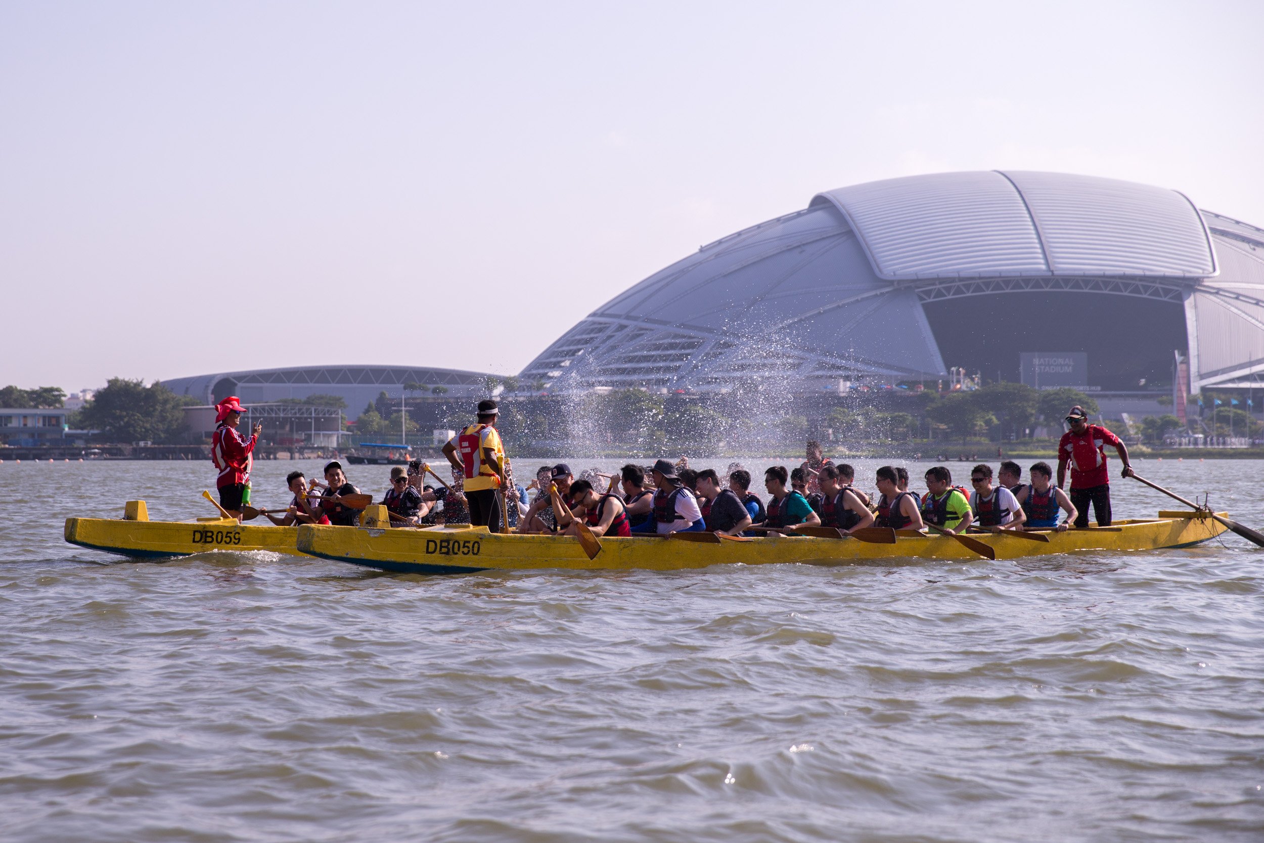  Friendly water battle with participants on two passing dragon boats splashing water with their paddles. 
