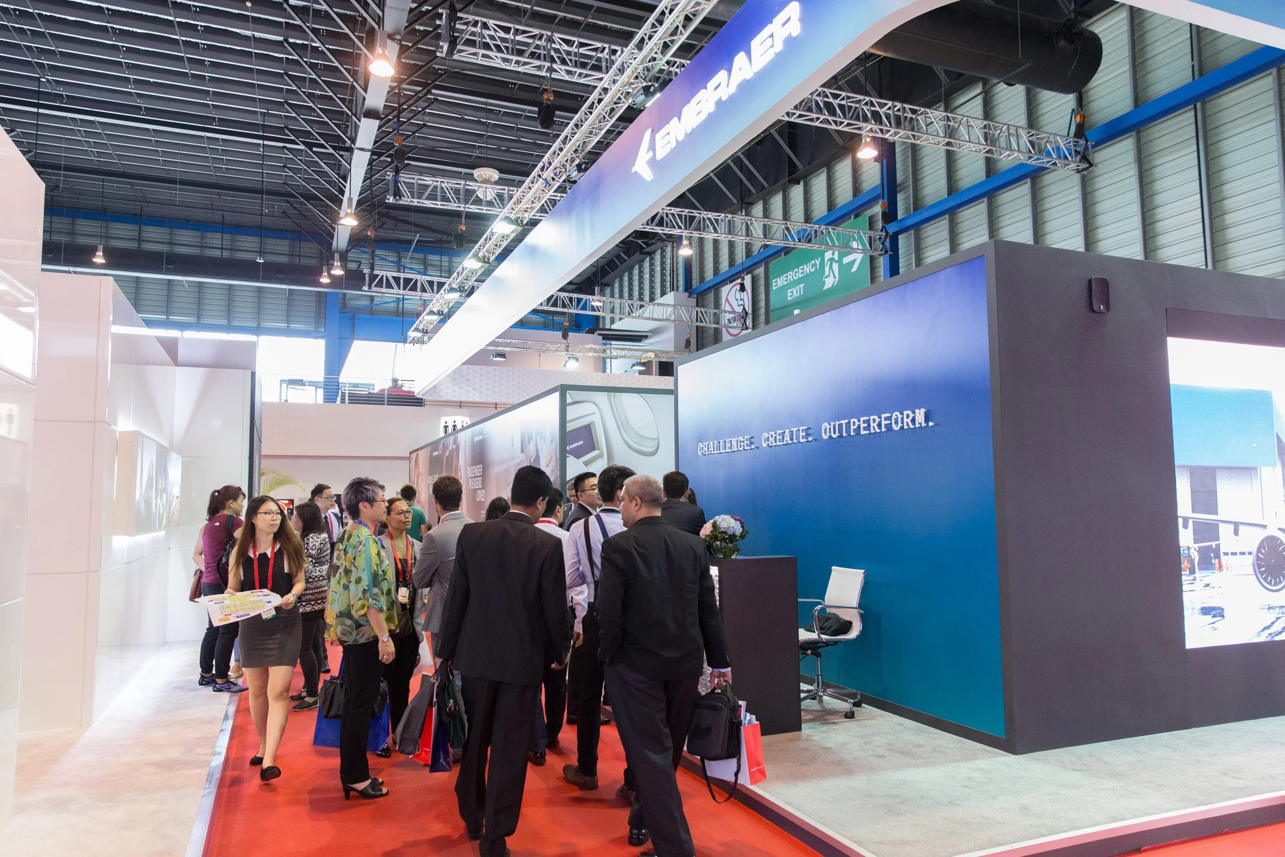  Eye-level wide shot of trade attendees and corporate booths inside the main Singapore Airshow exhibition hall. 