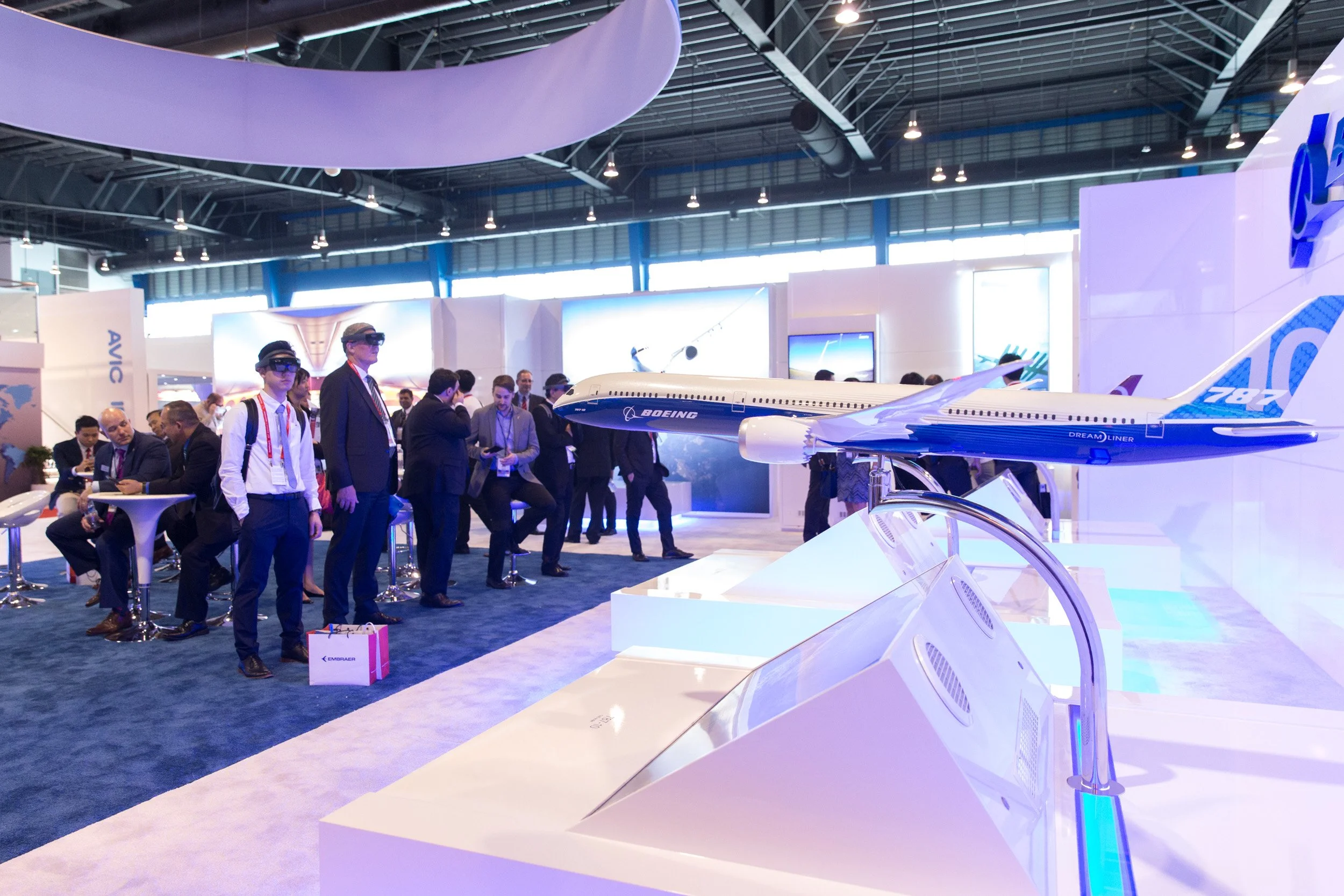  Exhibition hall overview showing aircraft scale models and visitors testing virtual reality aerospace technology. 