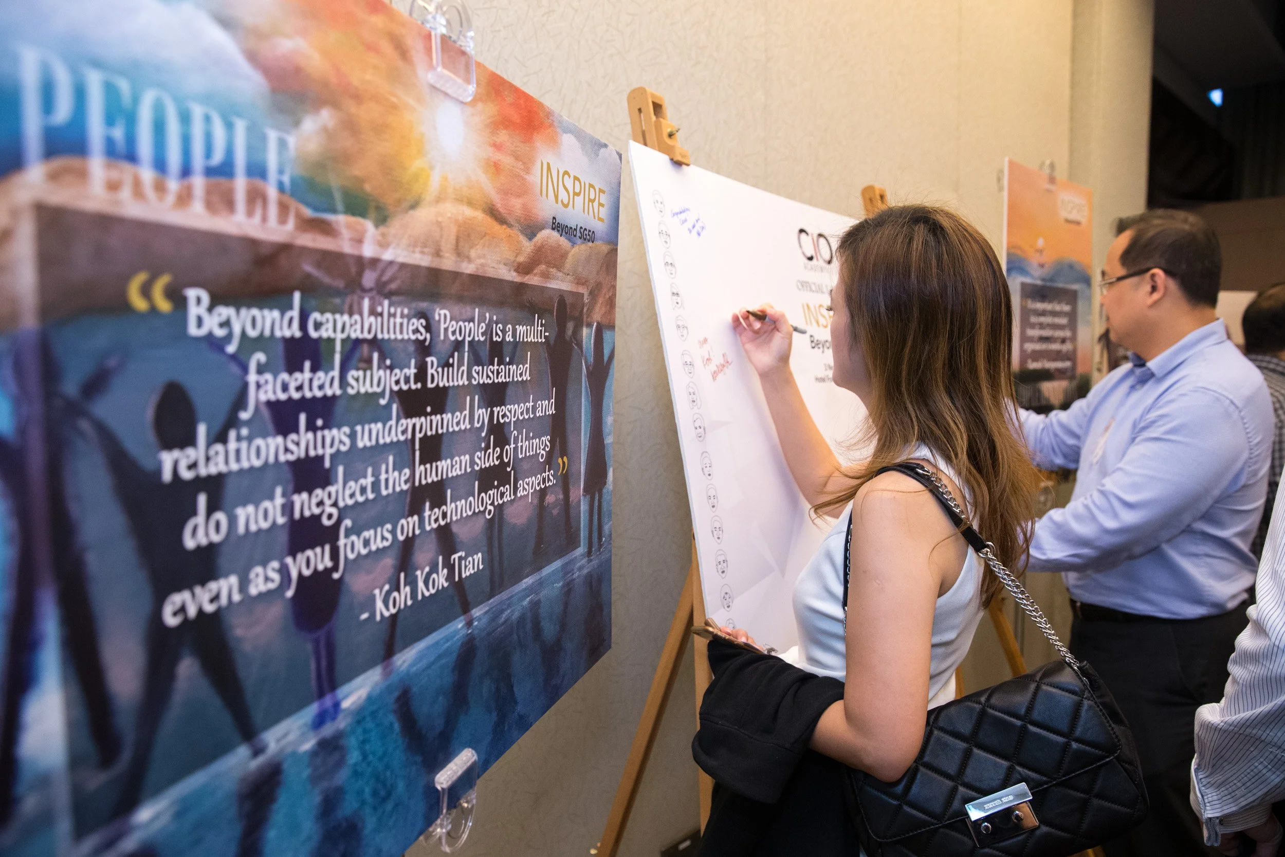  Event attendees penning congratulatory messages on the interactive message board near the entrance foyer. 