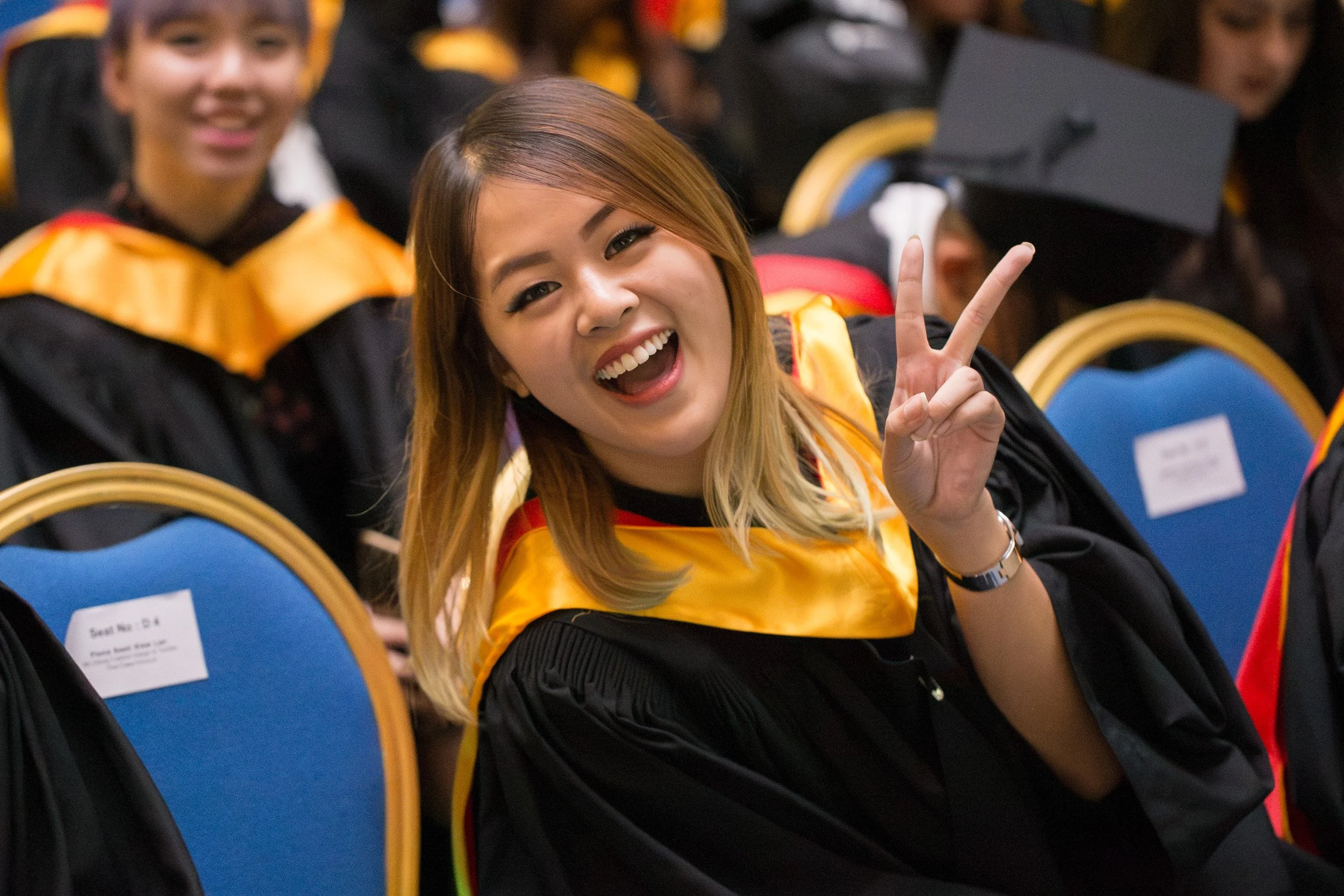  Candid portrait of a smiling female LASALLE graduate wearing academic dress and mortarboard cap. 