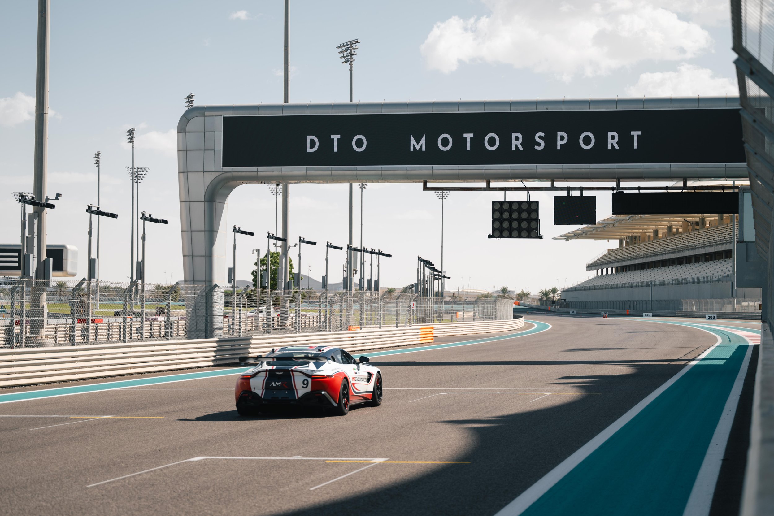 Race car on the track at DTO Motorsport circuit with grandstand and tower in the background.