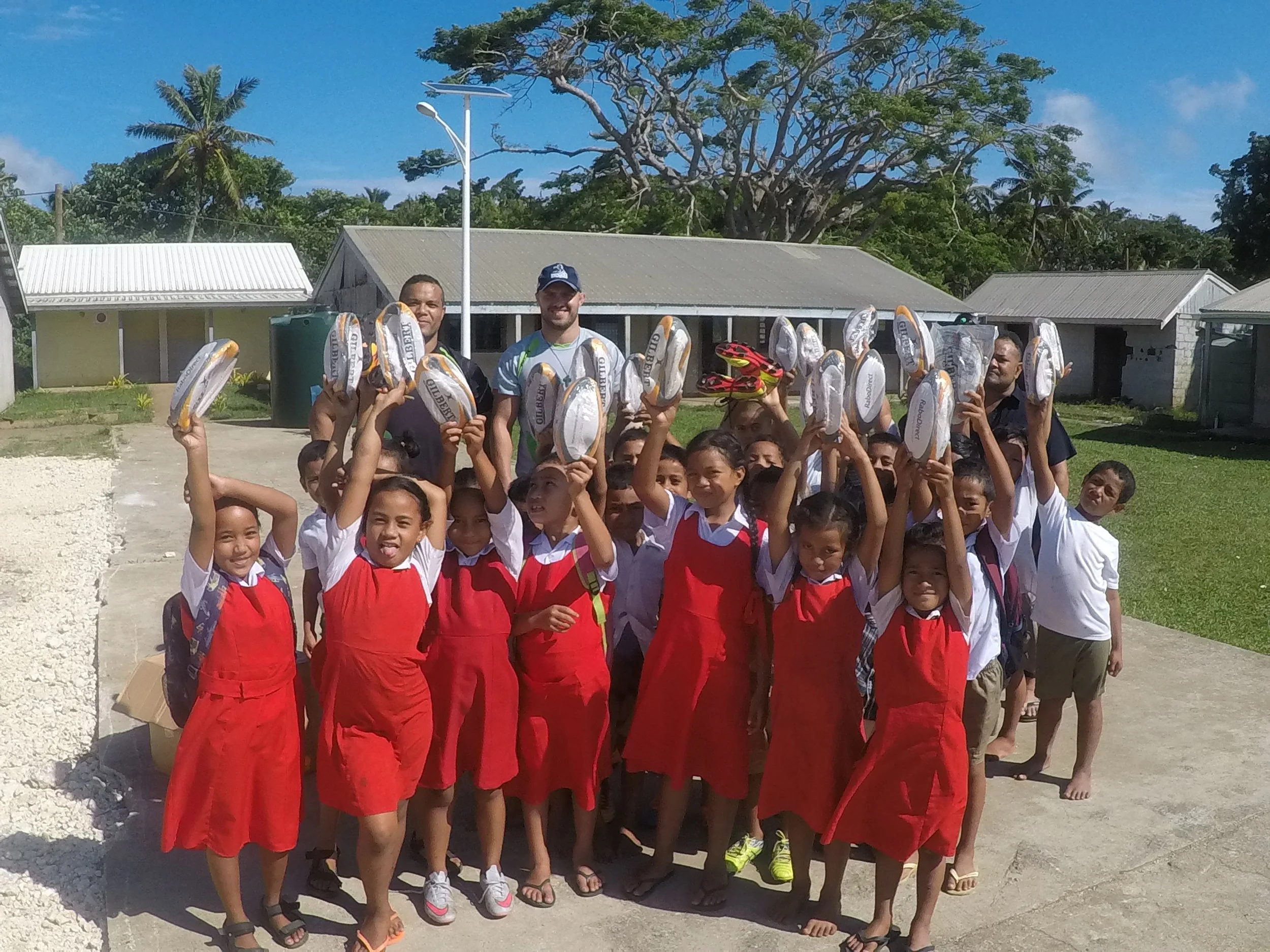 Handing out rugby balls to young girls and boys at a local school - lots of smiles!