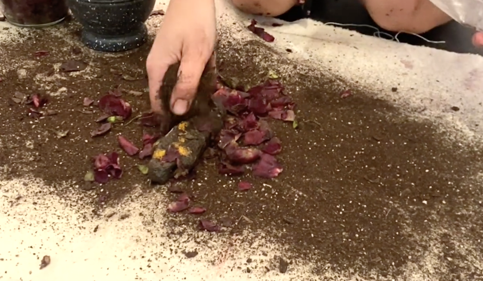 Your grief is welcome her e, 2025, still from performance documentation. I buried and unburied a small form based on a grain mummy, made from paper pulp, soil, and crushed roses. Before burying the form, I rubbed it with crushed roses and oil, insp