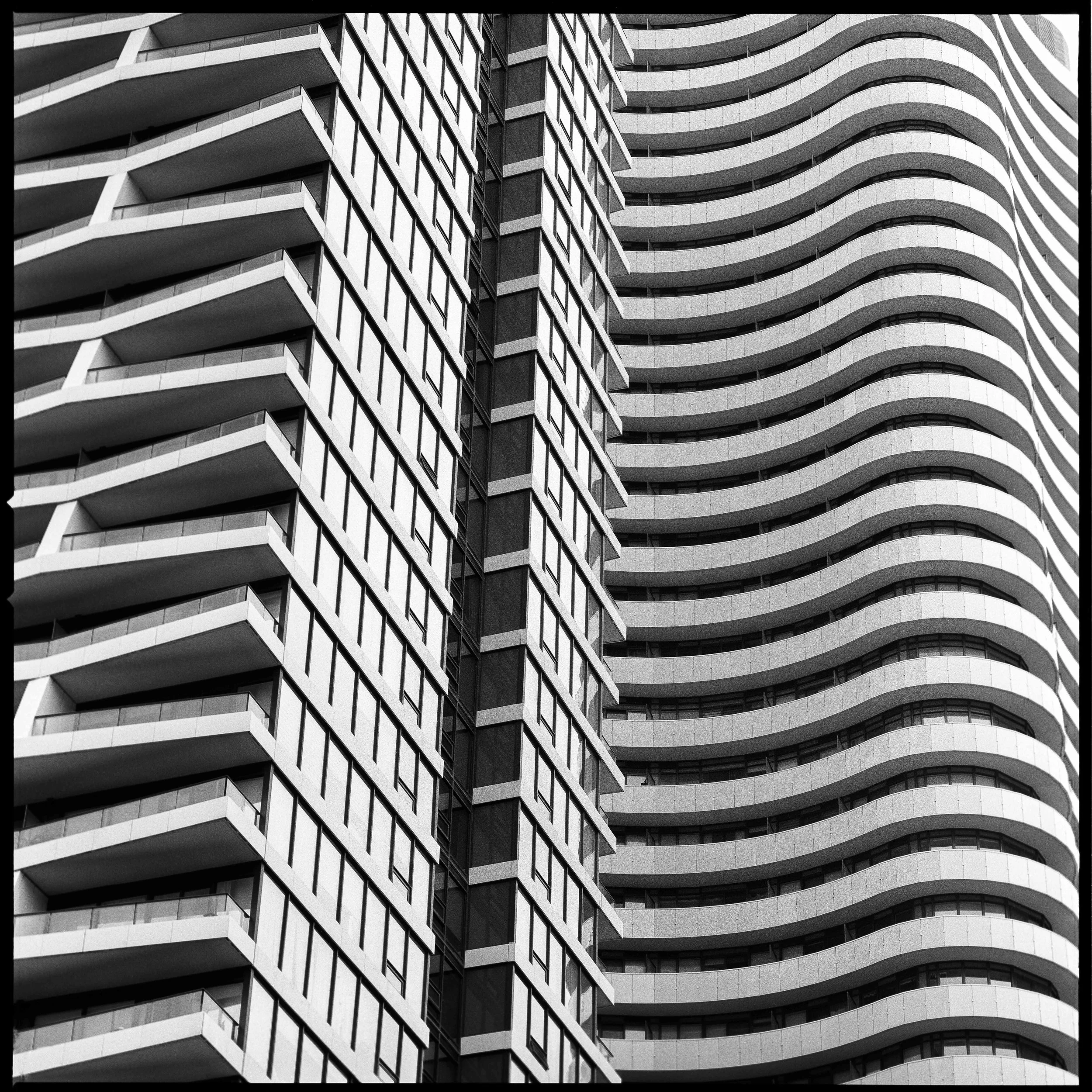 Close-up perspective of modern high-rise buildings with curved balconies, captured in black and white street photography by David Stokes.