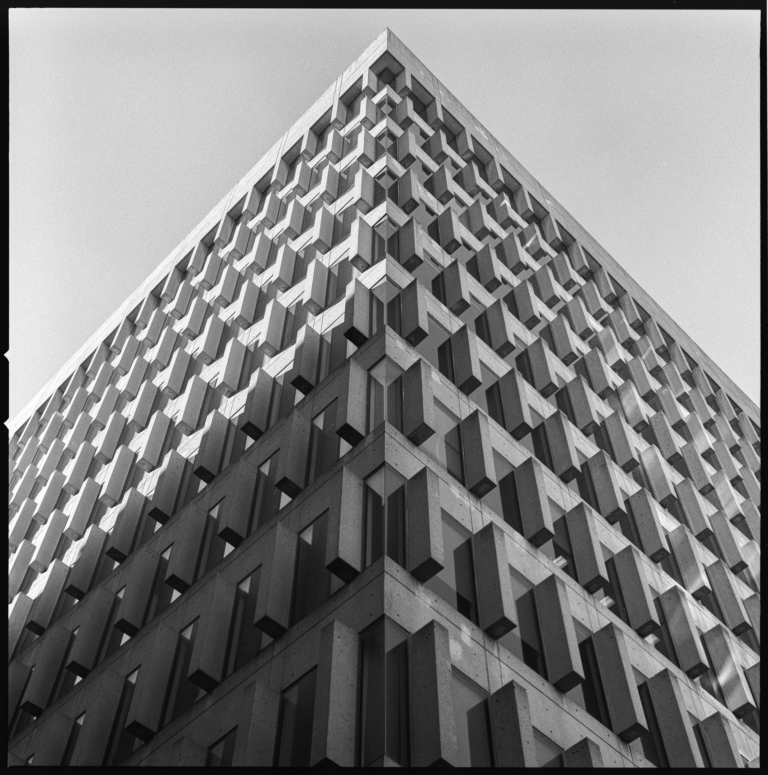 Perspective shot of a modern building with geometric patterns, captured in black and white street photography by David Stokes.