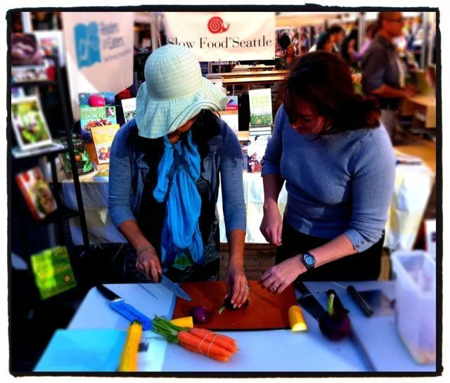 June Lee (left) tries her hand at cutting an onion like a chef after Kathleen Flinn's (right) demonstration.