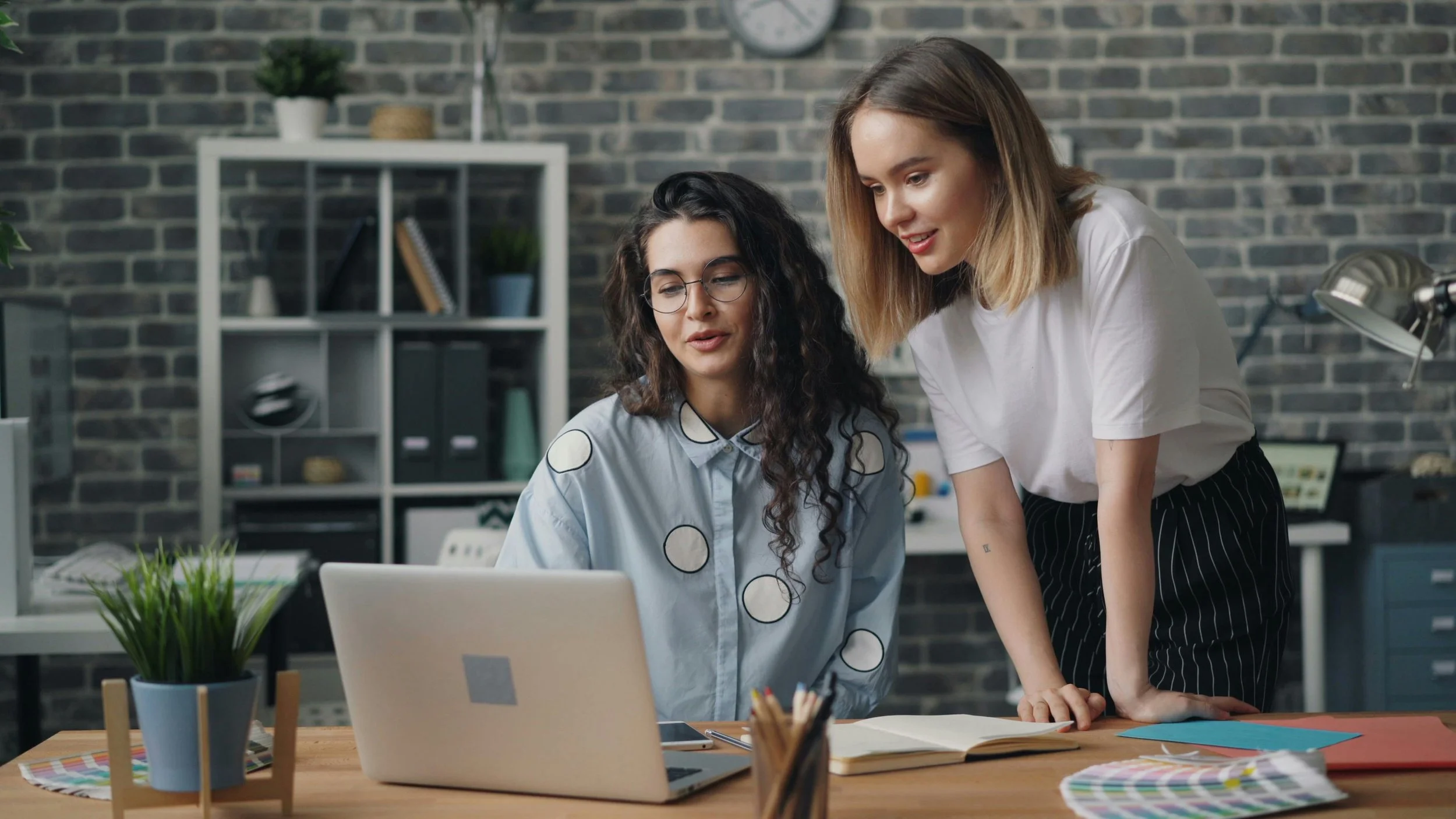two young women smiling and looking at a computer