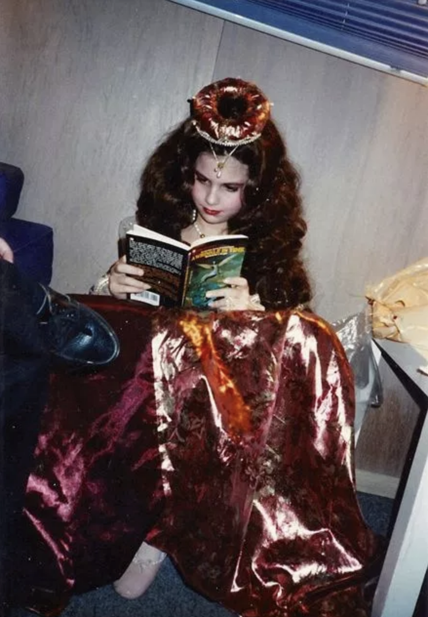 Lisa on set dressed as a princess reading a book