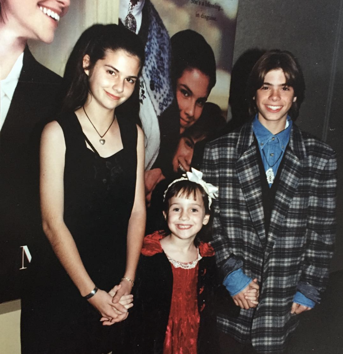 From the premiere of Mrs. Doubfire. Lisa stands with Mara Wilson and Matt Lawrence. They are all holding hands. 