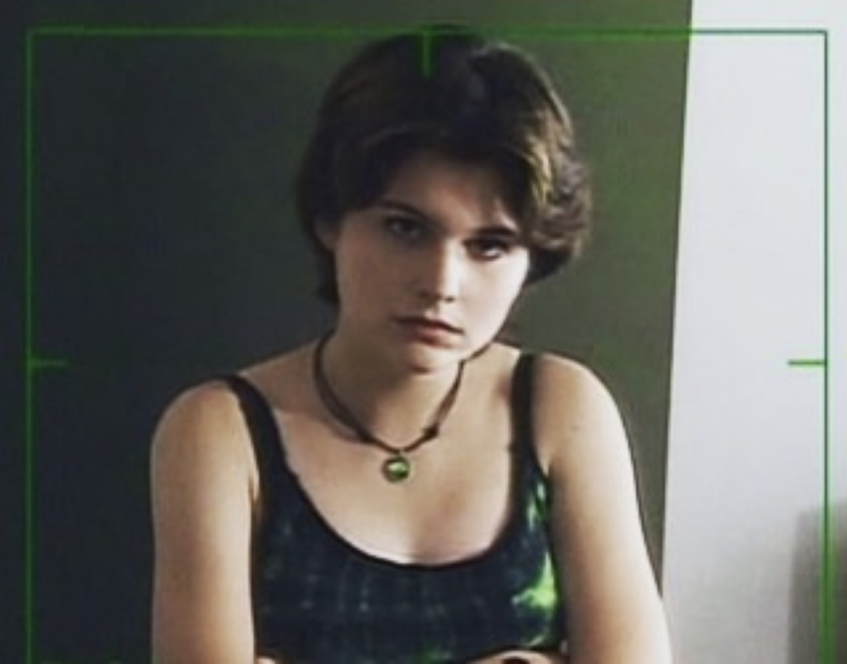 Lisa in the TV movie Dream House. Wearing a tank top and green necklace. 