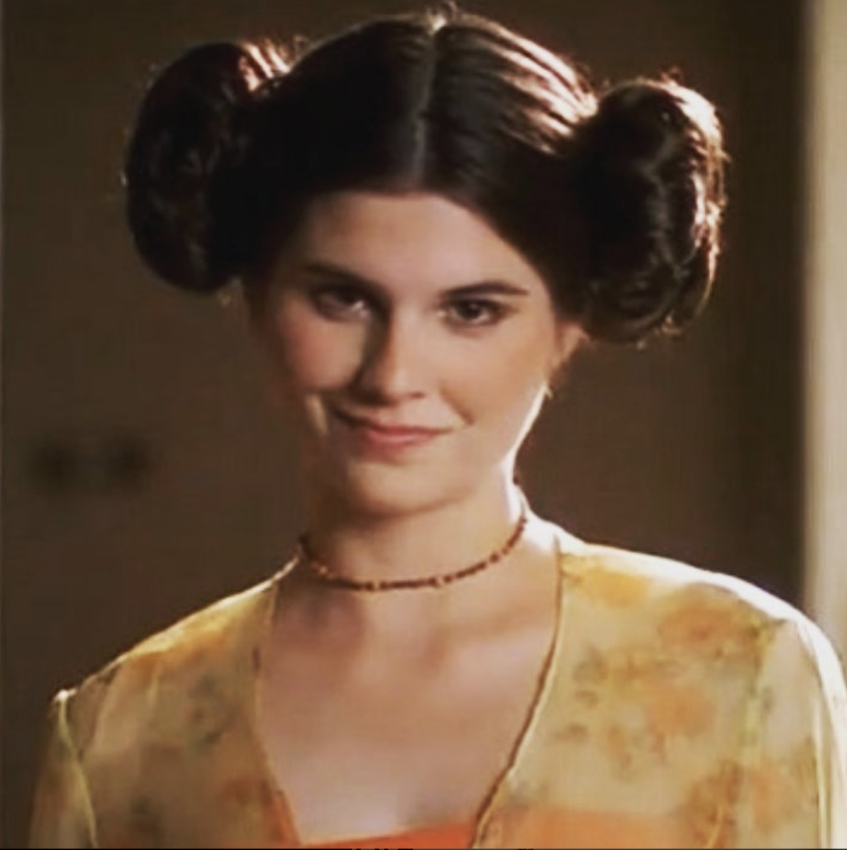 From George Lucas in Love. Lisa smiles while wearing a yellow top, and hair buns like Princess Leia