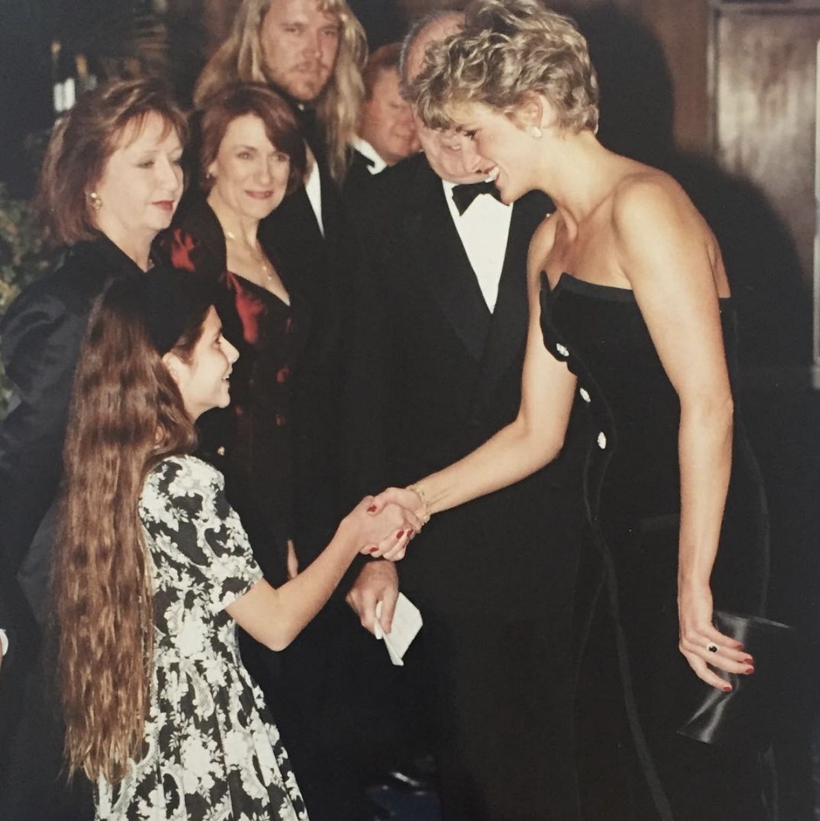 Lisa Jakub meets Princess Diana and curtseys, as they both smile. 