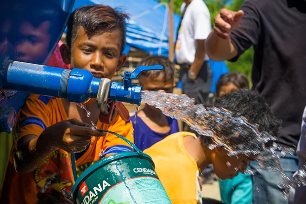 A boy gets water from a CWS truck. He is one of more than 13,000 people who CWS delivers water to each day.