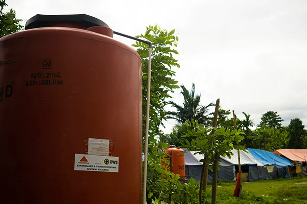 A CWS-provided water tank. Behind it are tents, where survivors who lost their homes are living temporarily.