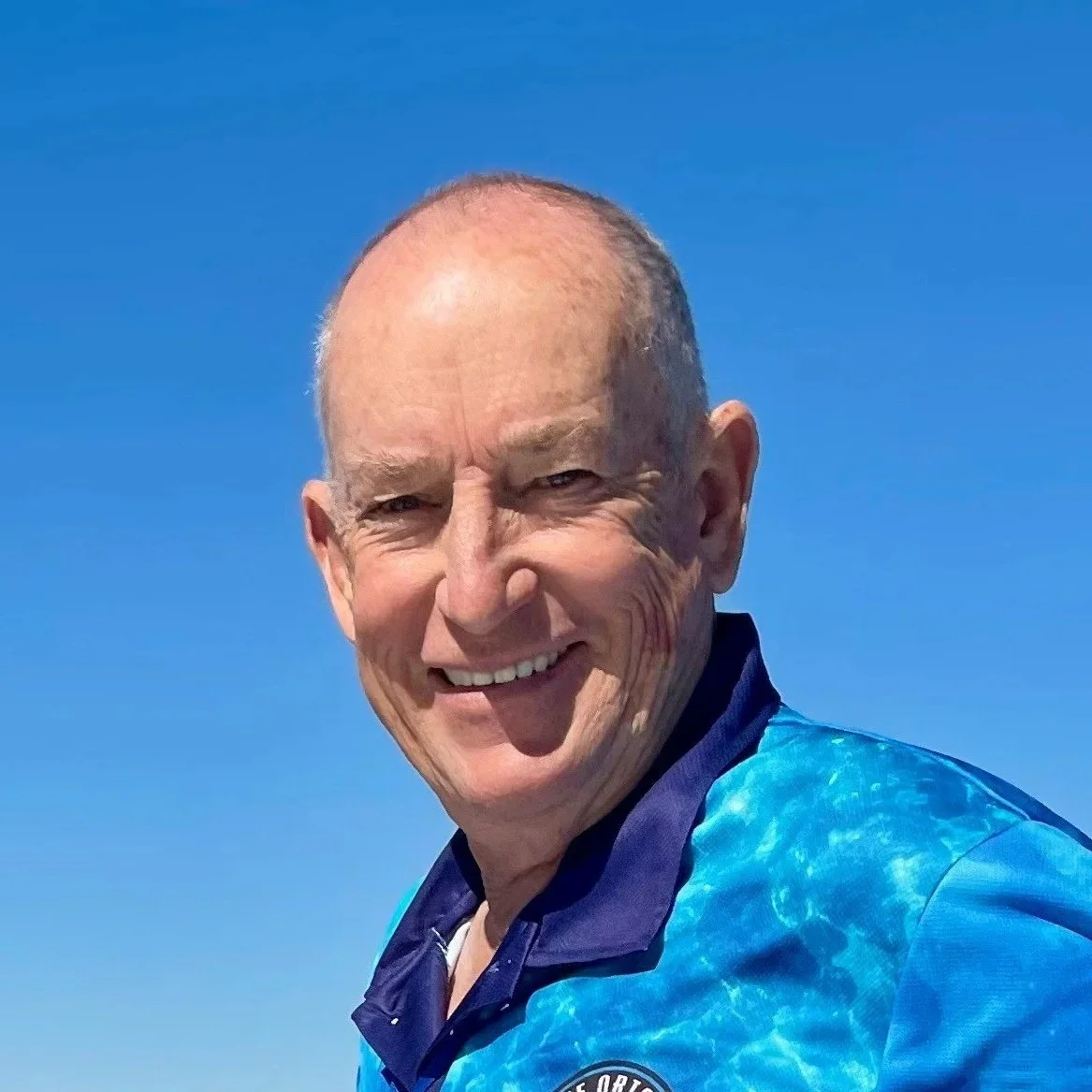 A photo of Ian on a blue background smiling at the camera
