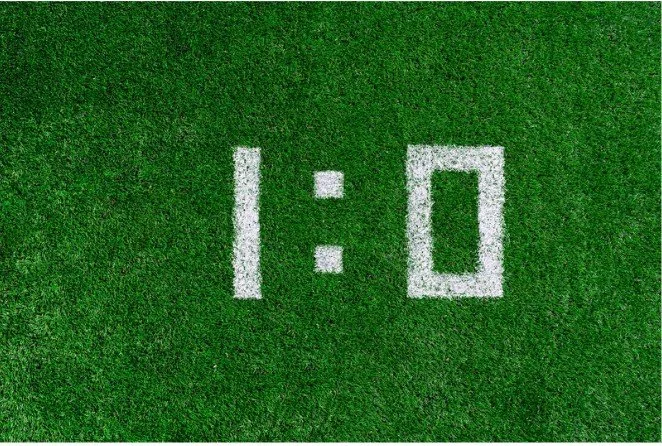 A green field with the image of a score in white, 1:0