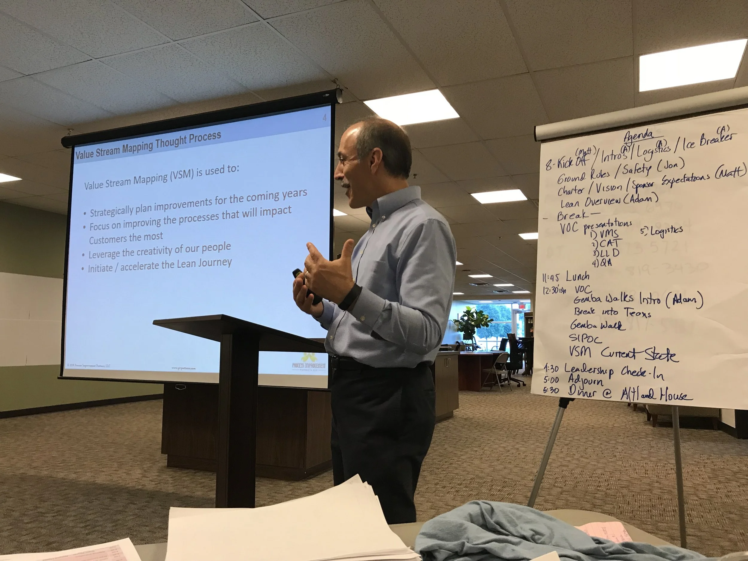 Adam Lawrence, owner of Process Improvement Partners LLC, located in Lancaster Pennsylvania, speaking in front of a screen describing Value Stream Mapping
