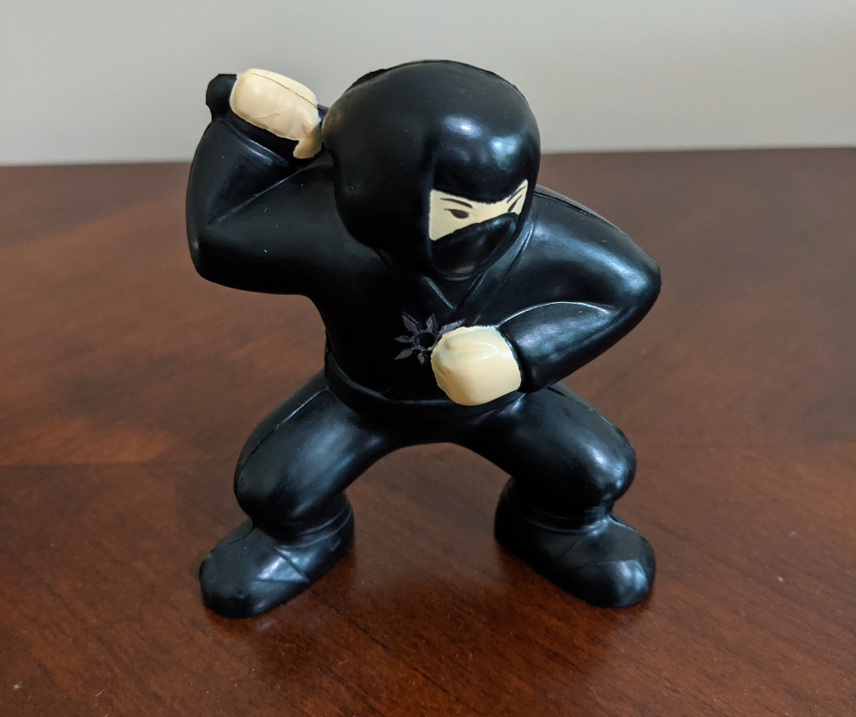 A picture of a Ninja stress reliever that I hand out to all of my team members. It's on a brown desk surface.