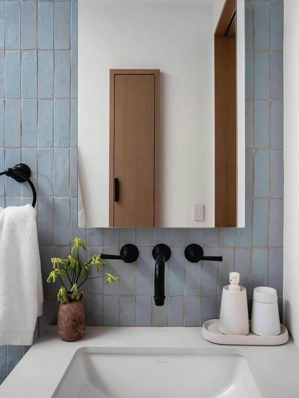 Blue tiled wall by a sink and mirror