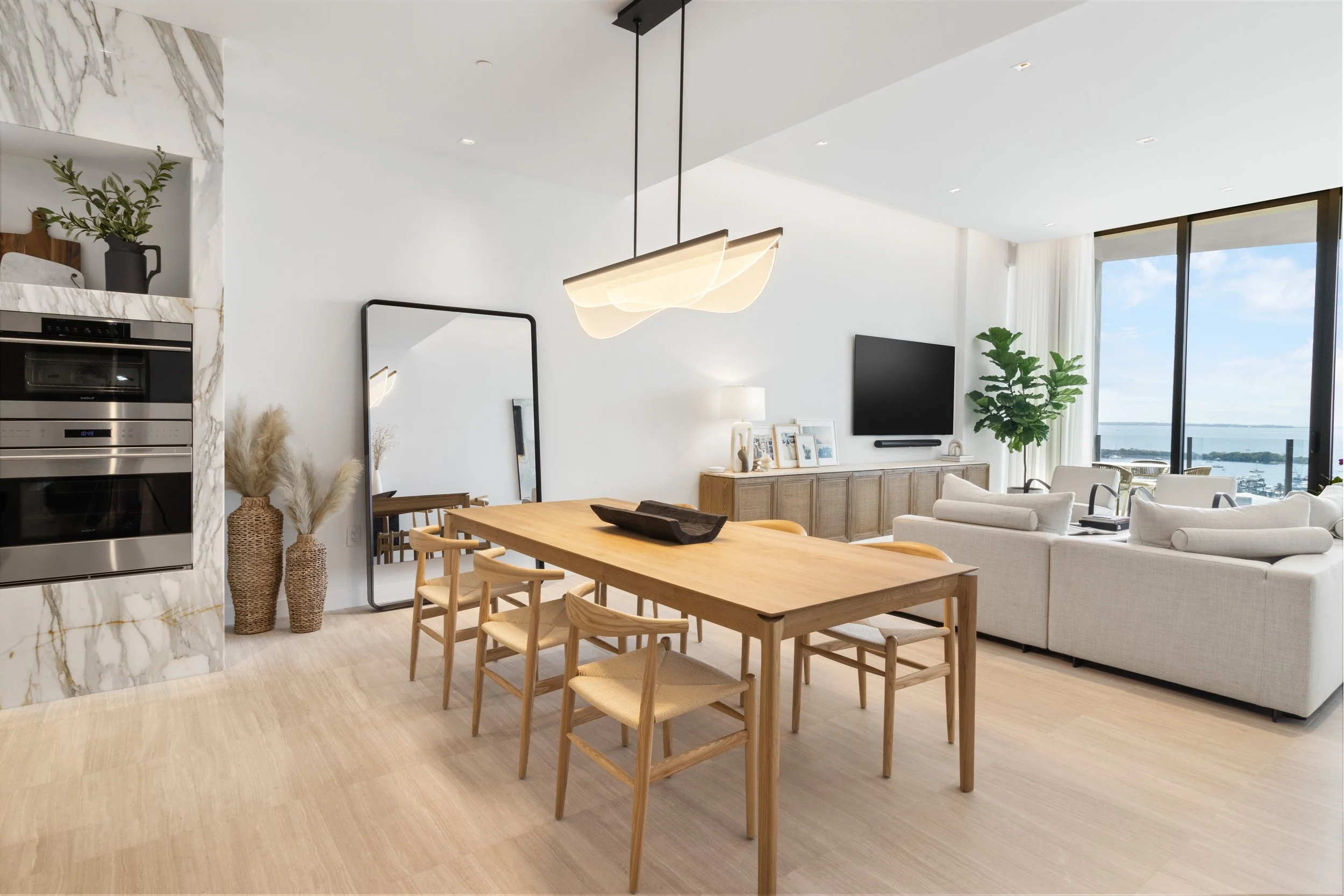 Modern open kitchen and dining room with warm woods, light finishes, and refined detailing in a Coconut Grove luxury condominium, Miami interior design.