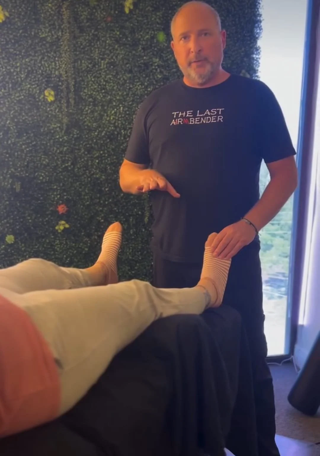 Dr. Eran Kabakov treating foot pain in a clinical setting looking at the camera