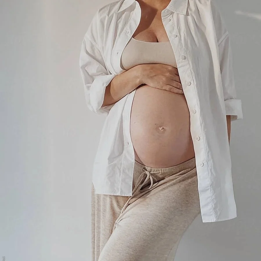 Close up of a pregnant woman's belly with a bouquet of flowers, representing the best fertility acupuncture practice in San Diego, CA.