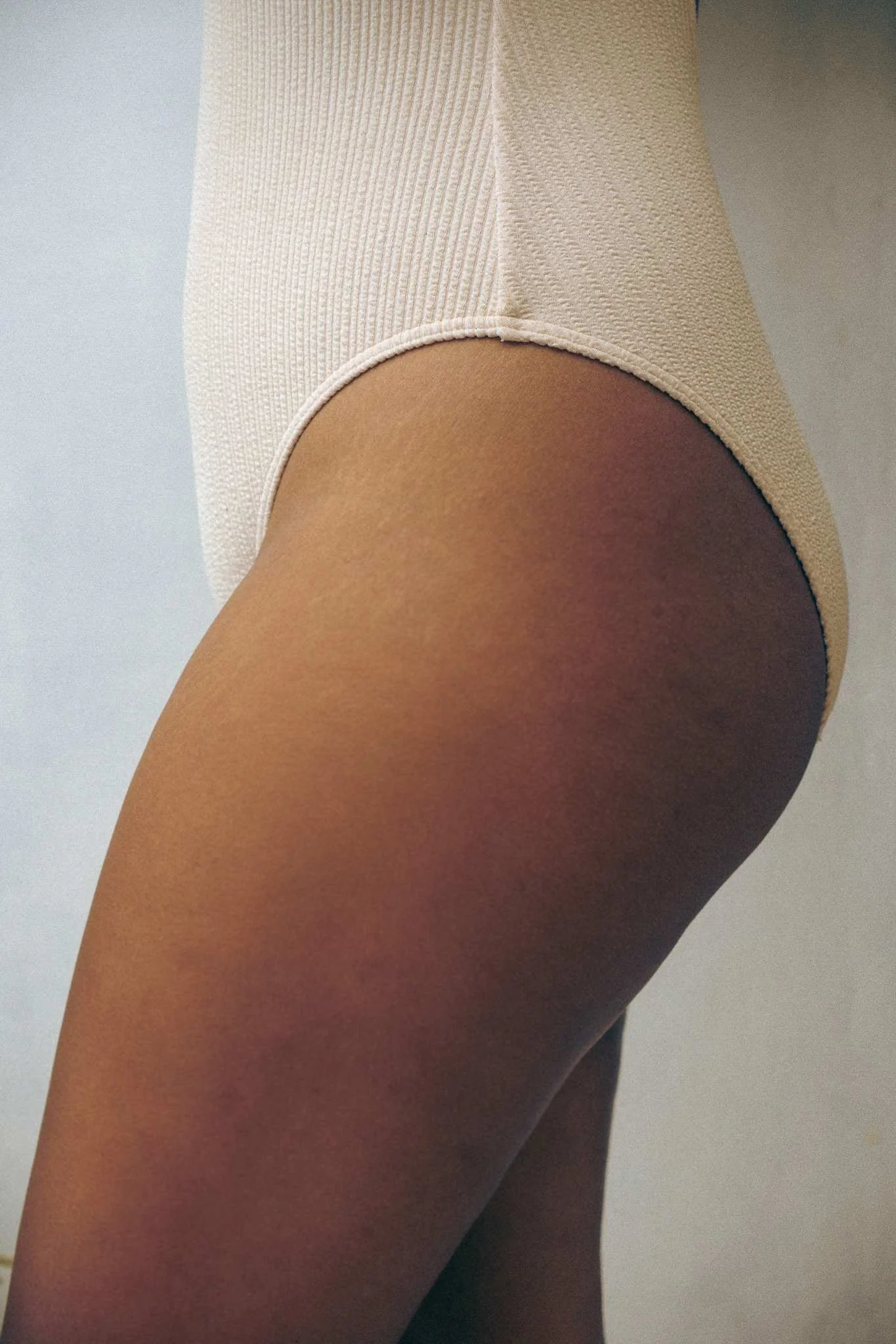 Close-up profile of a hip and thigh in a nude bodysuit, part of the body-centered care i IUI acupuncture care