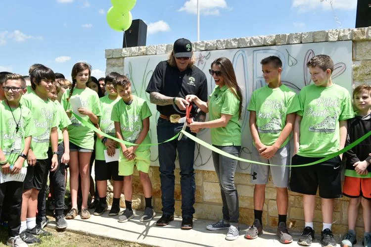 Chad Chance and Susan Chance are surrounded by students as they cut a ribbon during a dedication ceremony for Vail's Outdoor Classroom on Wednesday at Pilot Point Intermediate School.