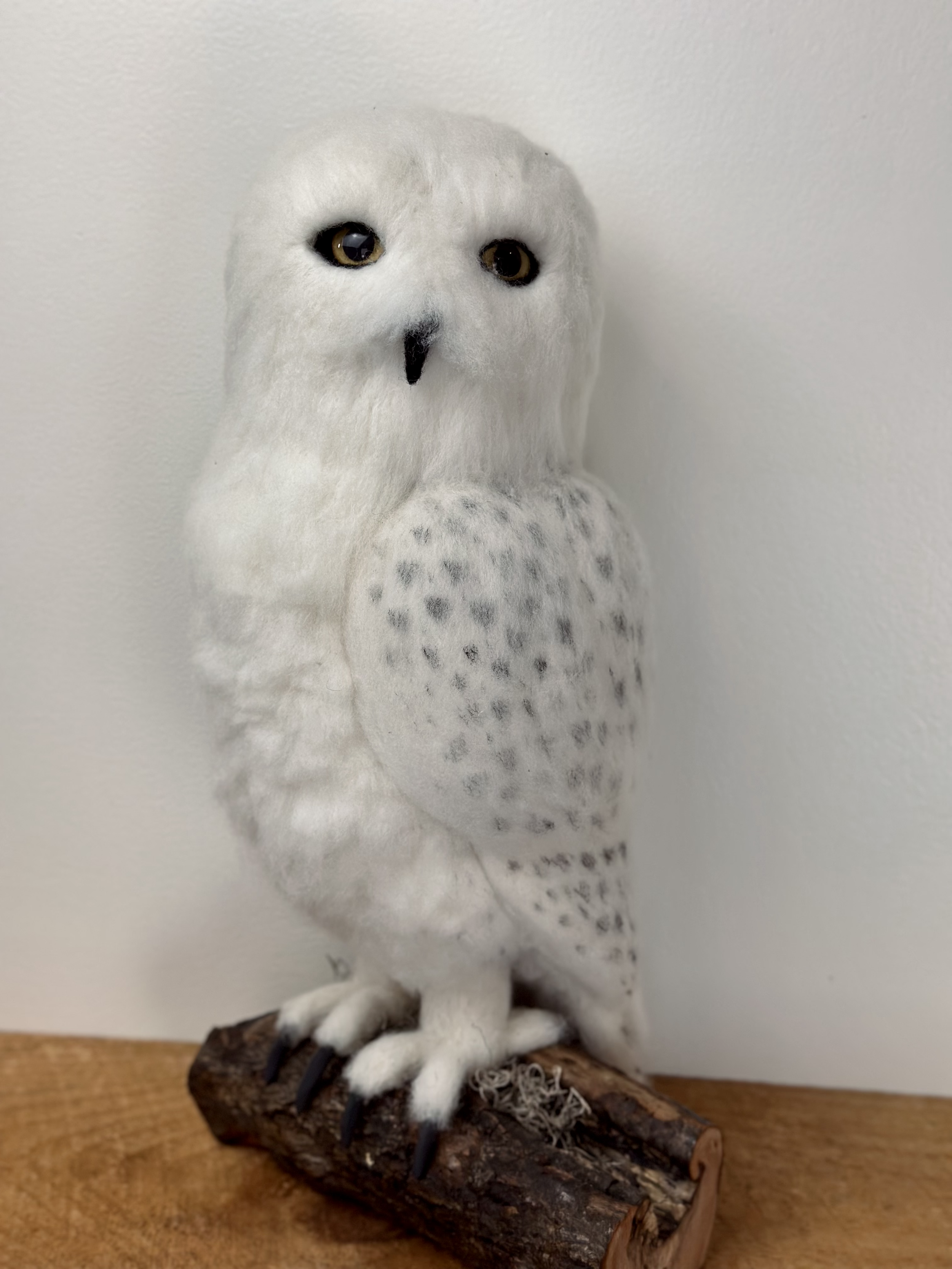 Life Size Snow Owl, handmade with Merino and Corriedale wool, perched on a log.